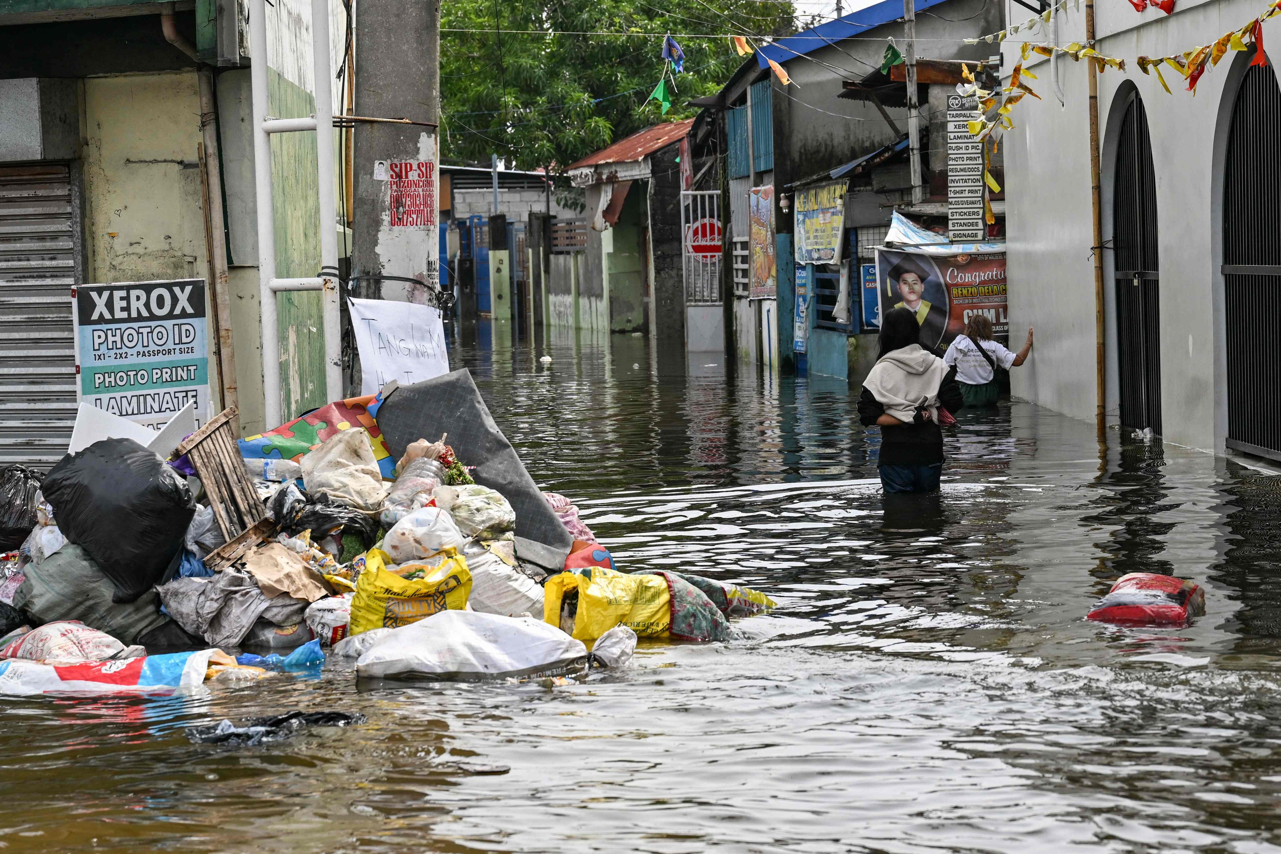 People wade through a flooded street after heavy rains brought by the southwest monsoon in Pampanga, the Philippines, on Monday. Photo: AFP
