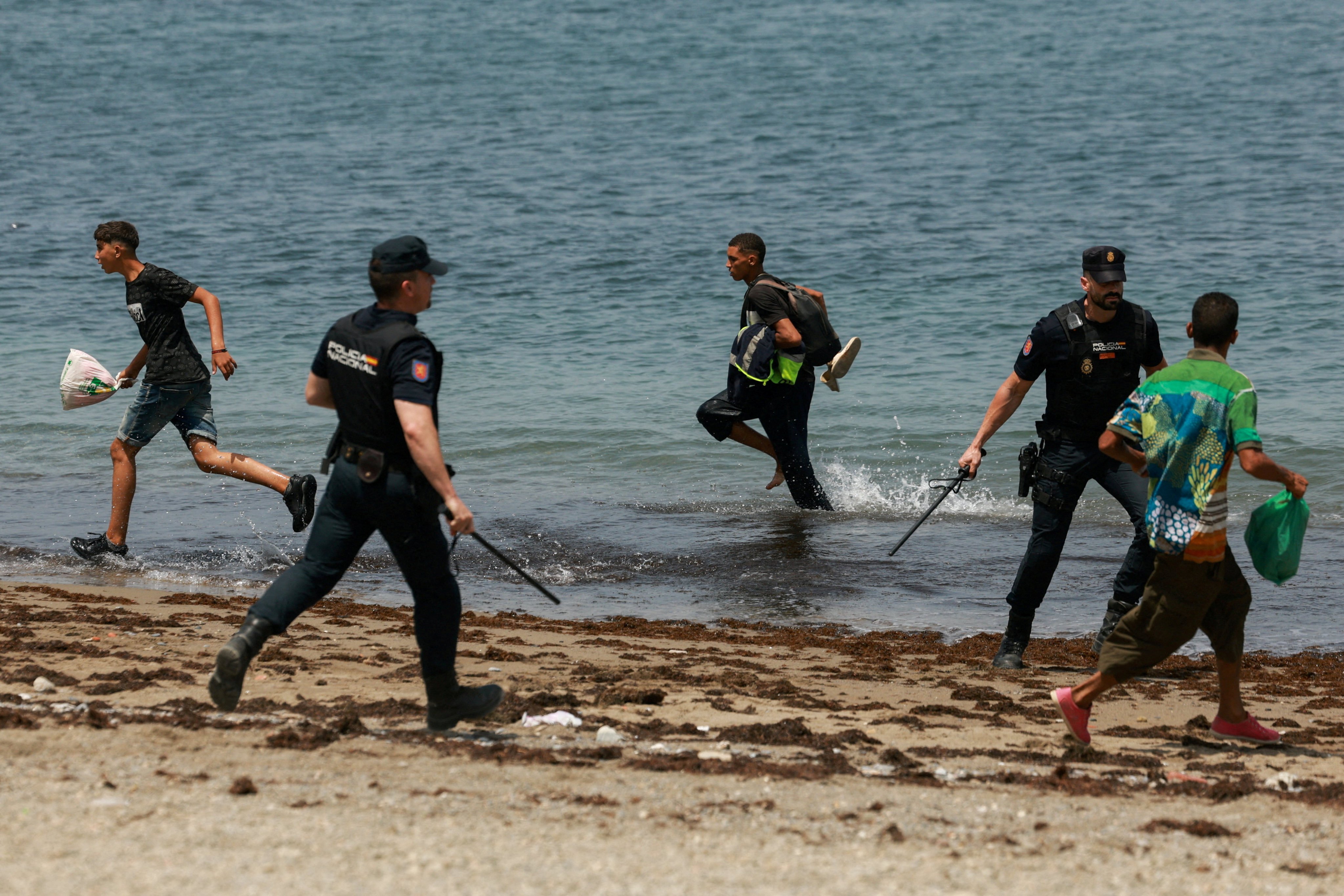 Migrants try to make their way past Spanish police officers on August 1, following recent mass crossings of migrants on foot and by sea from Morocco into Spanish territory, in Ceuta. Photo: Reuters