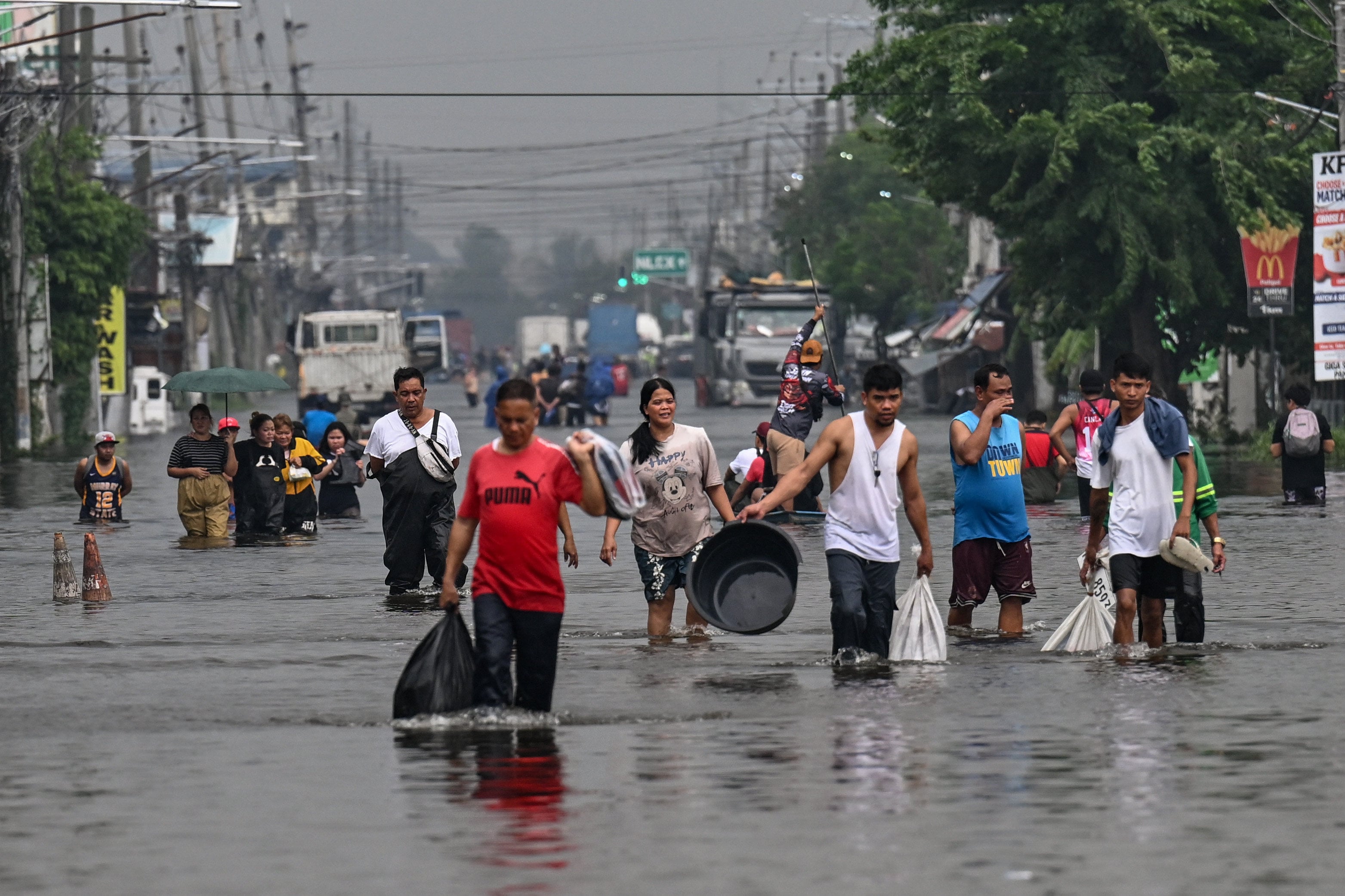 People wade through a flooded street after heavy rains brought by the southwest monsoon in Pampanga, the Philippines, on Monday. Photo: AFP