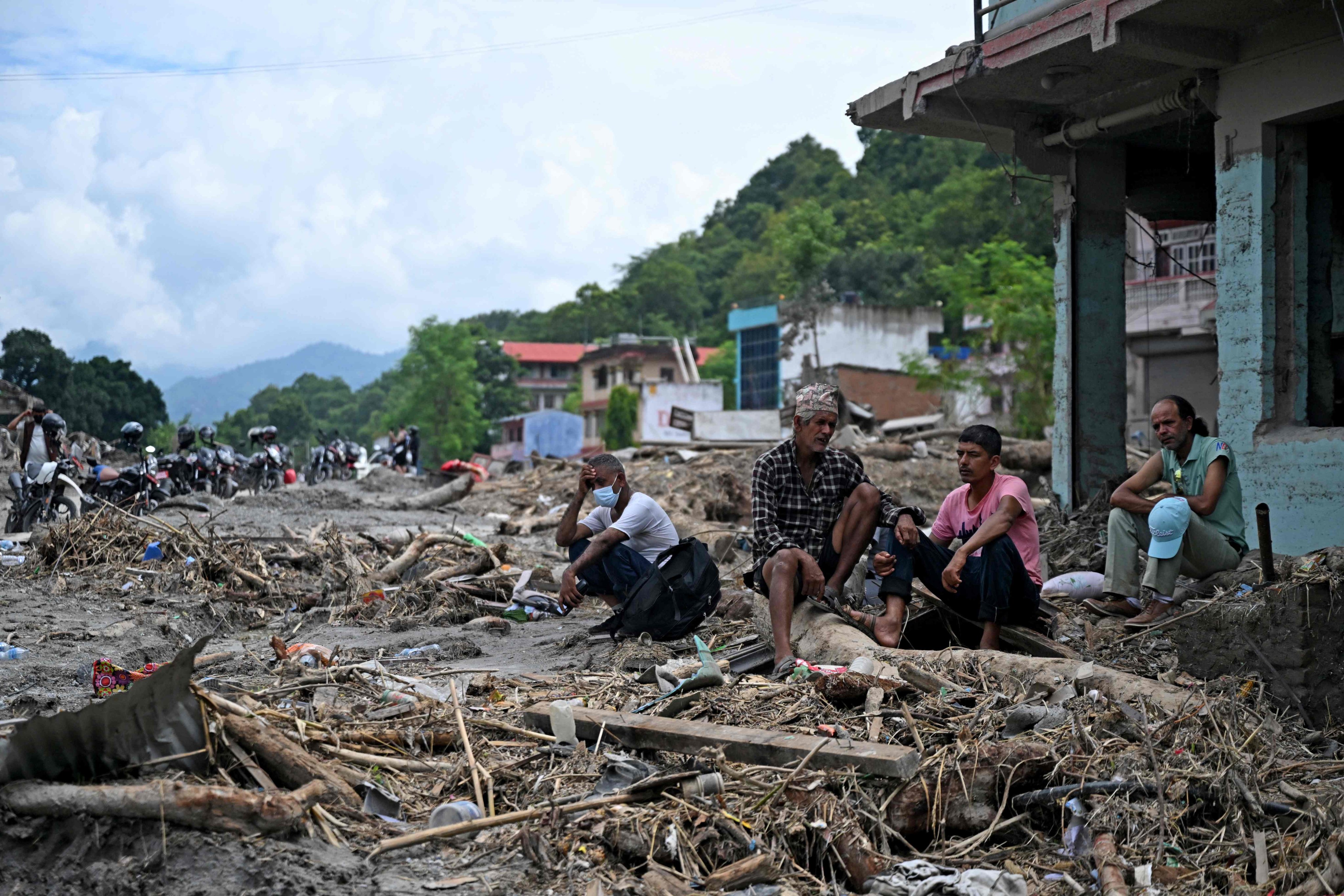 Residents sit beside debris as they salvage belongings following flash floods at Devighat in Nepal’s Nuwakot district on August 31. Photo: AFP