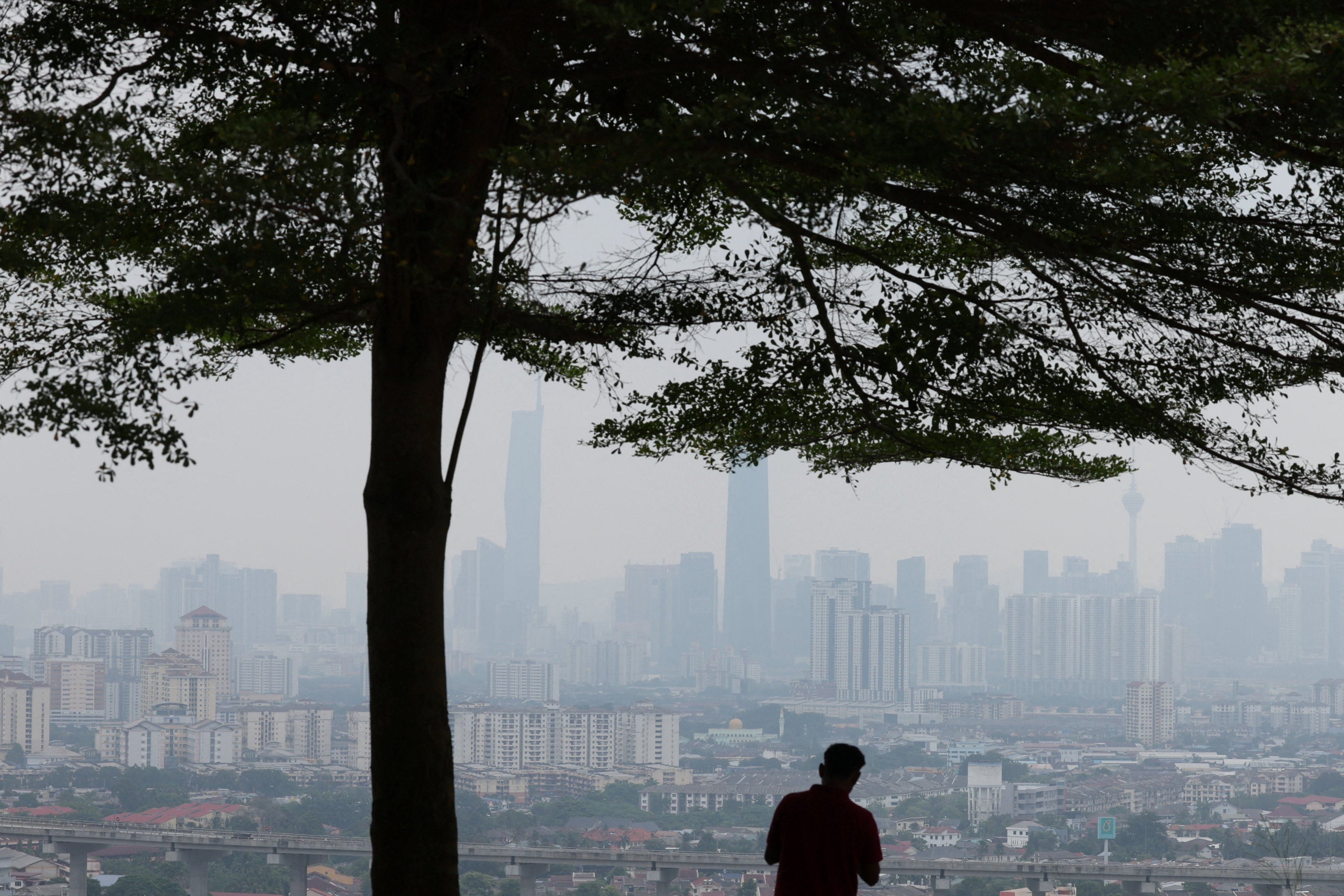 A man looks at Kuala Lumpur’s skyline shrouded in haze from regional wildfires on Wednesday. Photo: Reuters