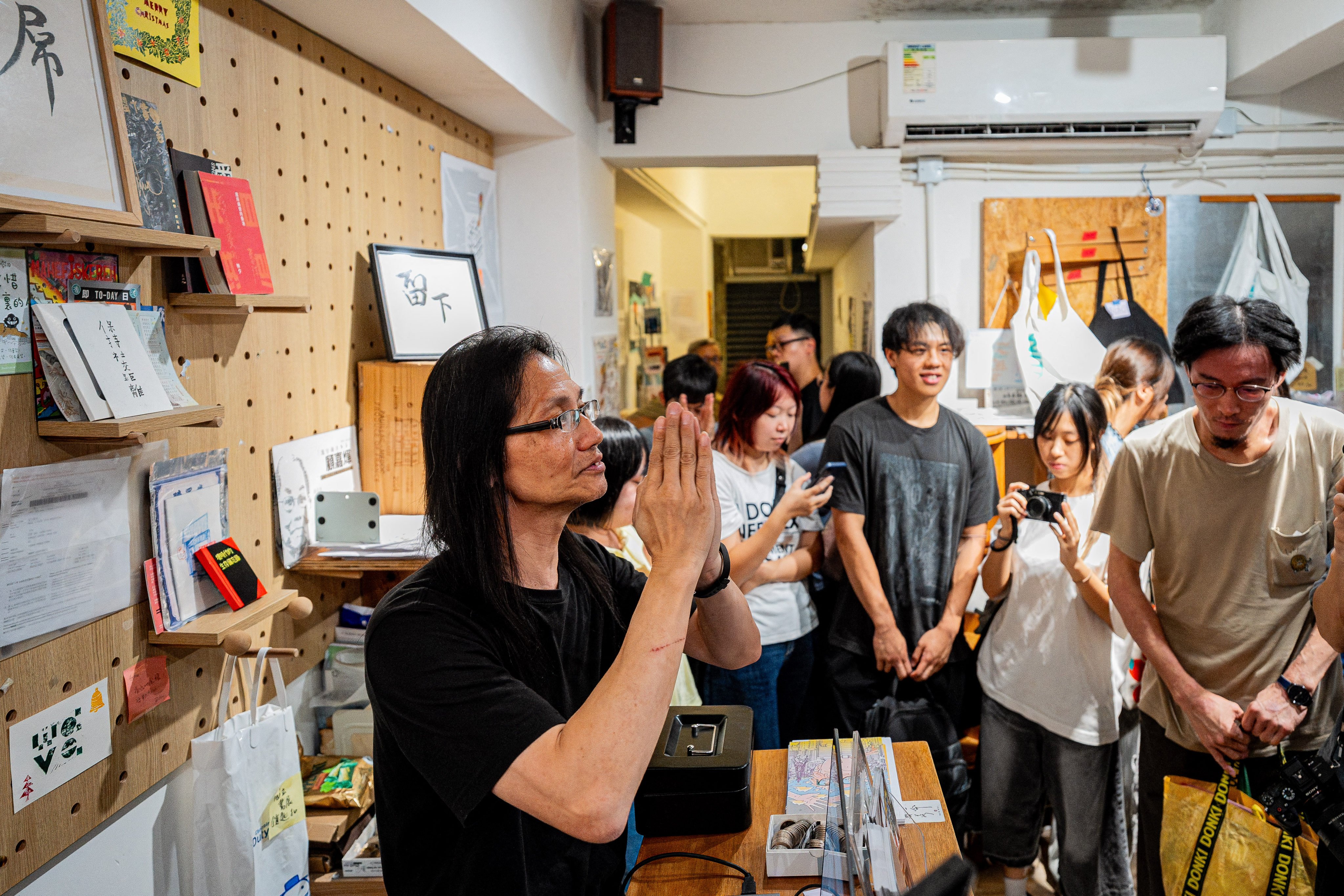 ‘Have A Nice Stay’ co-founder Sum Wan-wah (L) bids farewell to customers on the independent bookstore’s final day of operation, in Hong Kong on August 30, 2026. (Photo by Leung Man Hei / AFP)