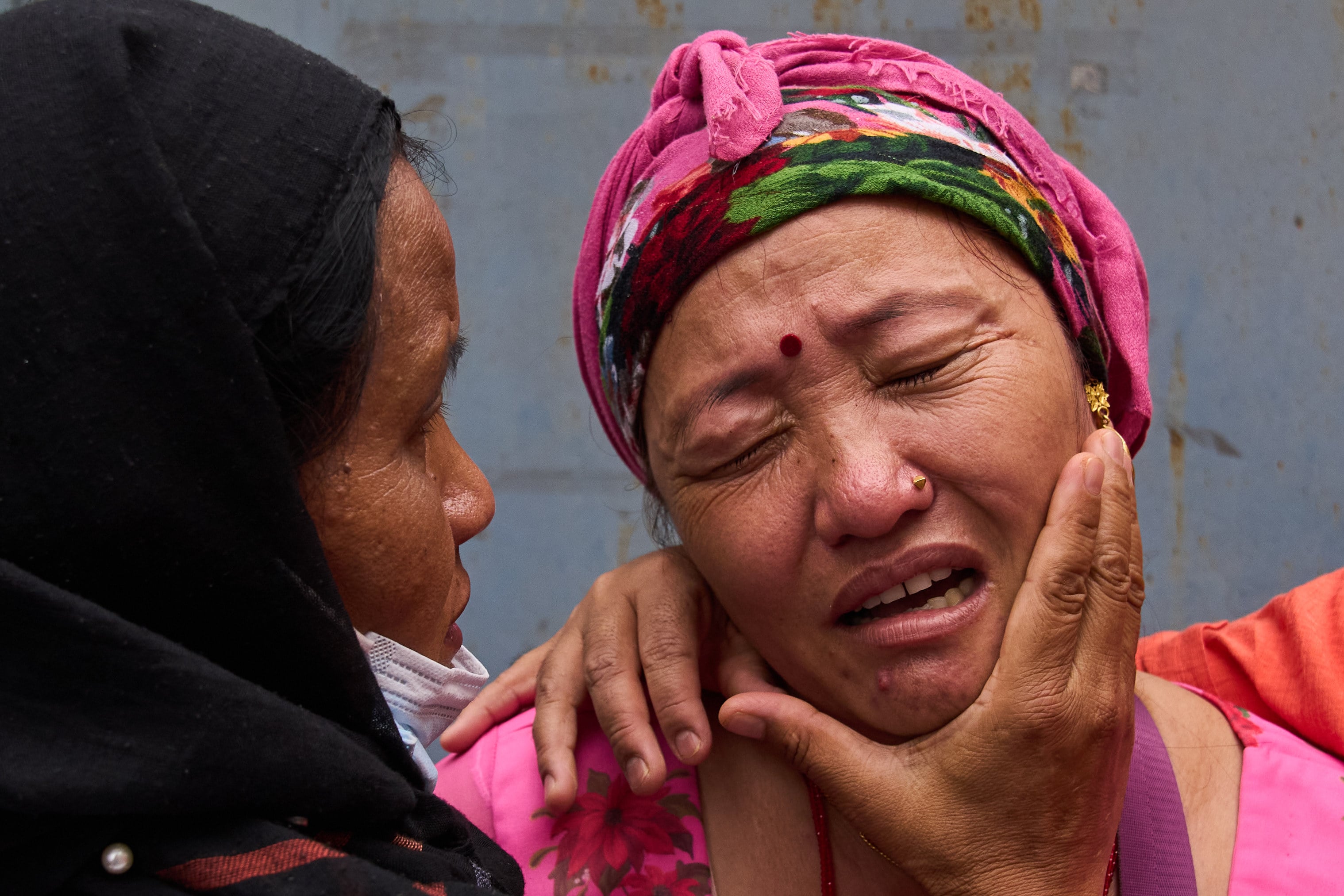 Relatives comfort Jantari Gurung, whose husband is missing, as she looks at photographs of people killed in flash floods displayed outside a government hospital in Kathmandu on Sunday. Photo: AP