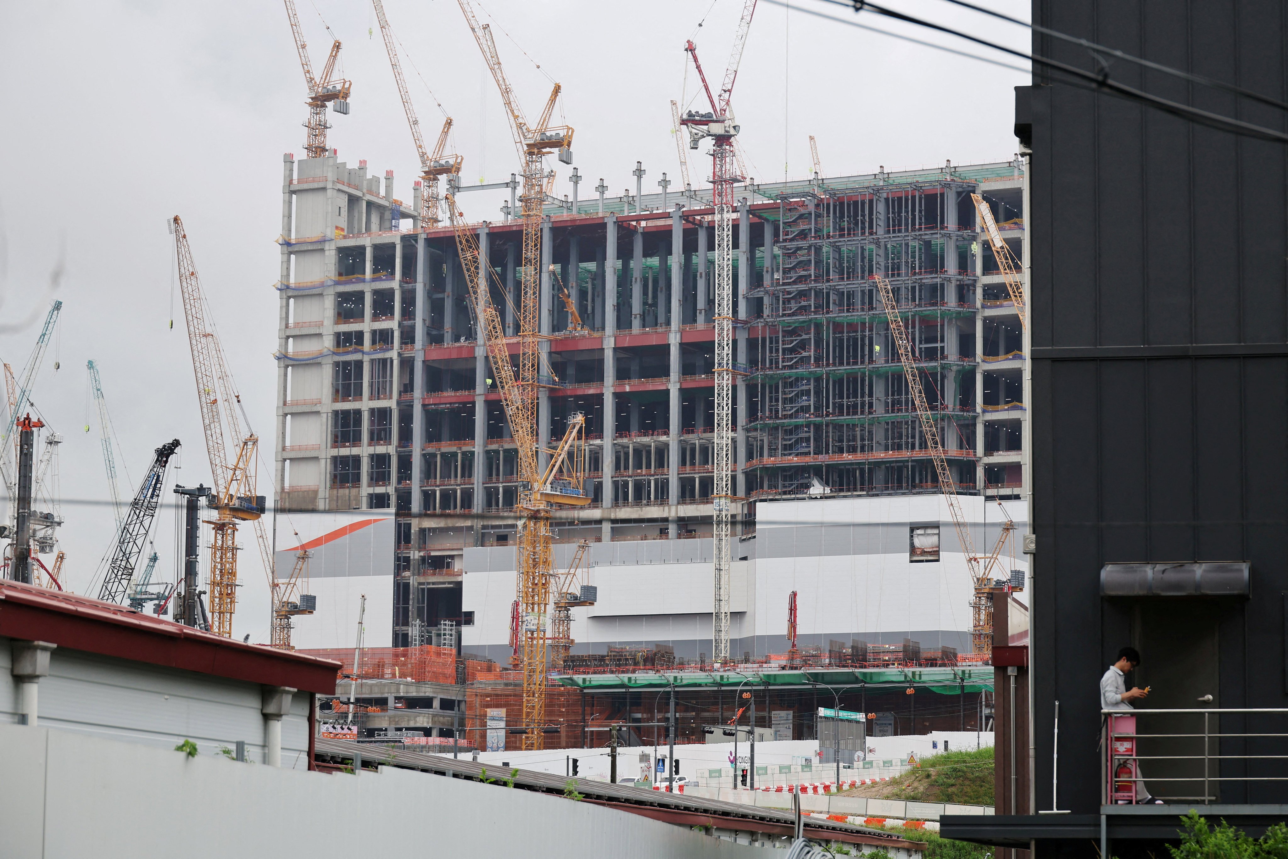A man uses his mobile phone with the construction site of the Yongin semiconductor cluster in the background on July 21. Photo: Reuters