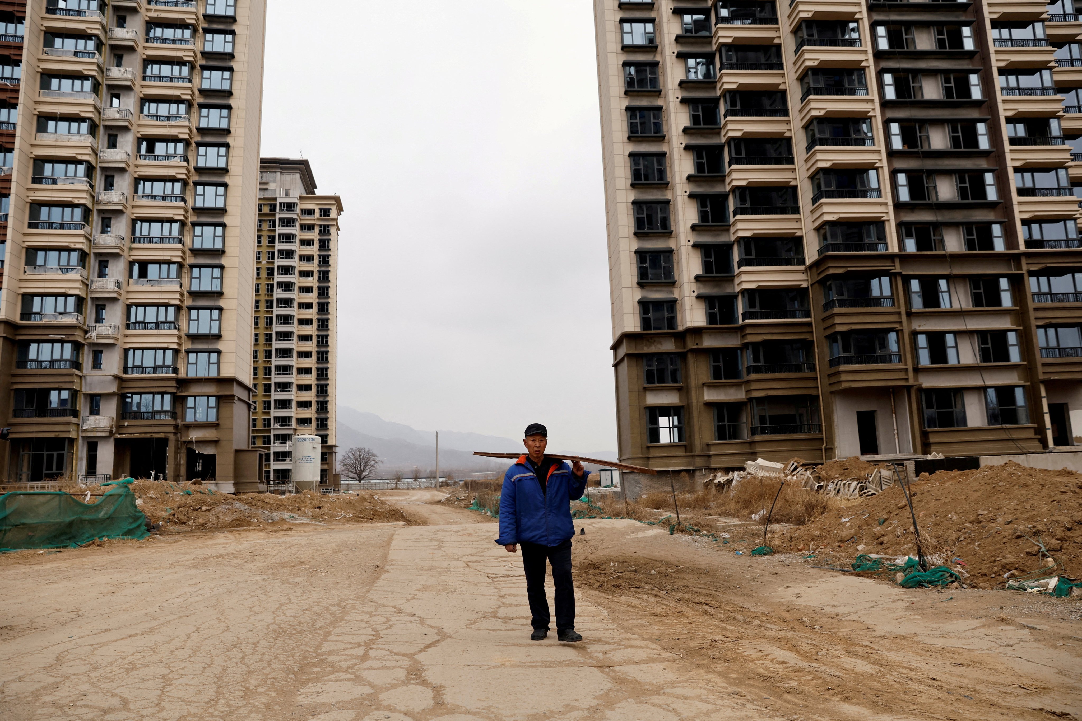 A man walks past unfinished residential buildings developed by China Evergrande Group in the outskirts of Shijiazhuang, Hebei province, on February 1, 2024. Photo: Reuters