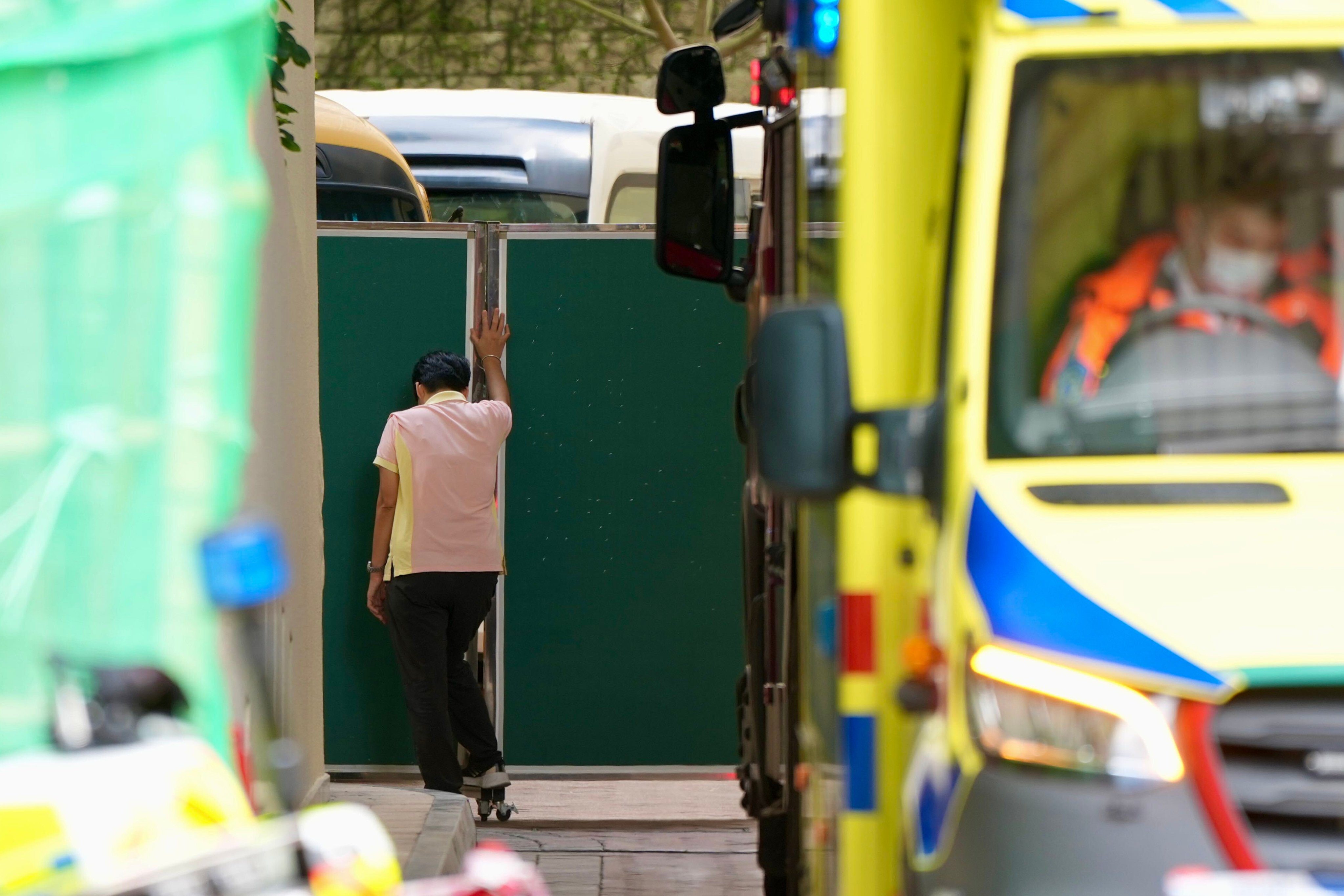 A member of staff stands before a wall of green panels concealing the accident site. Photo: Sam Tsang