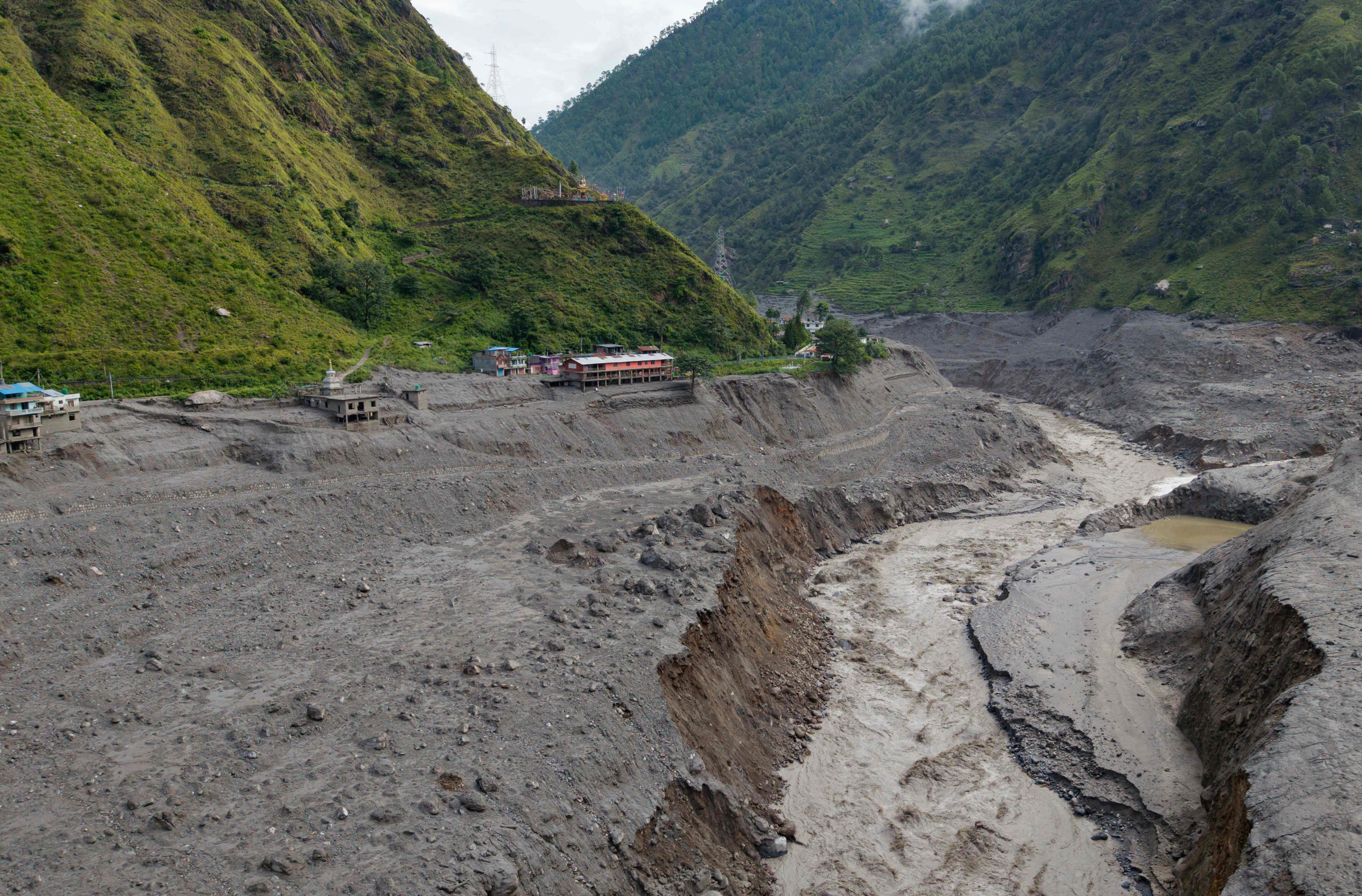 A torrent of muddy water surges past houses and through the Trishuli River in the aftermath of flash floods, near the Nepal-China border at Syabrubesi village in Nepal’s Rasuwa district on August 31. Photo: AFP