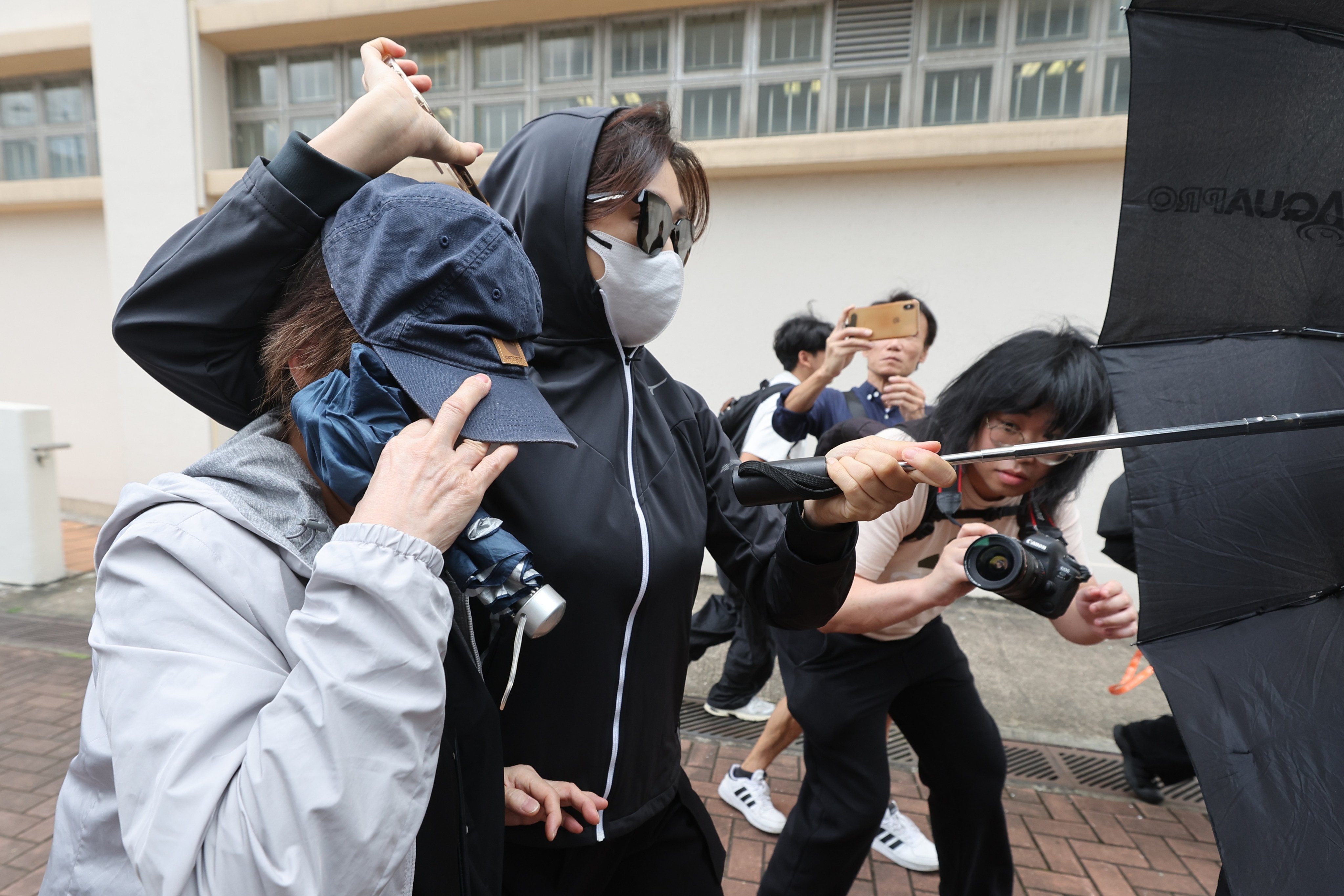 Leung Lai-ha adjusts her cap over her head as she leaves leave Kwun Tong Court with her daughter, Ng Ka-wun, on Thursday. Photo: Edmond So