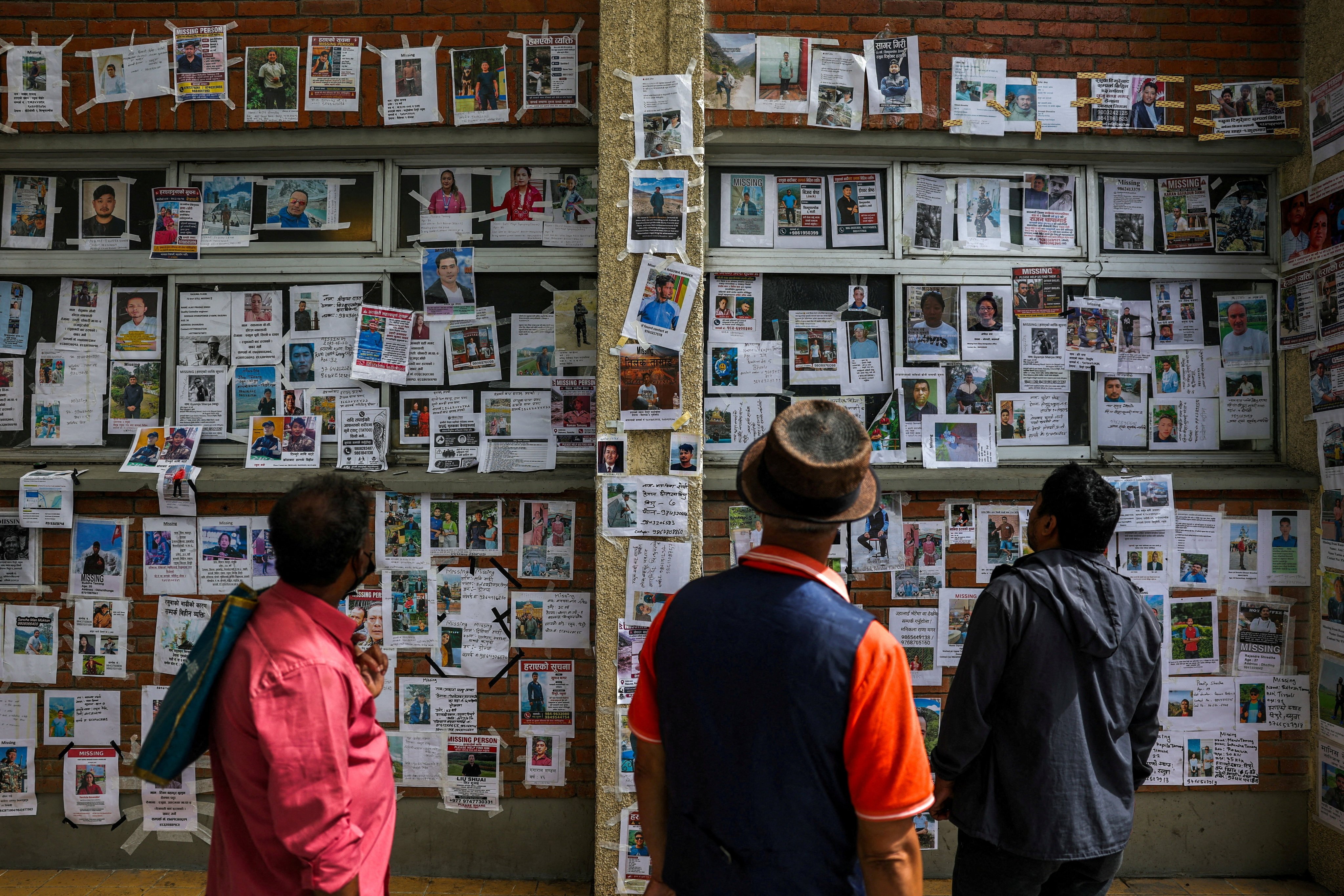 People look at photographs of missing people on a wall outside a hospital following the deadly flash floods and mudslide, in Kathmandu, Nepal, on Wednesday. Photo: Reuters