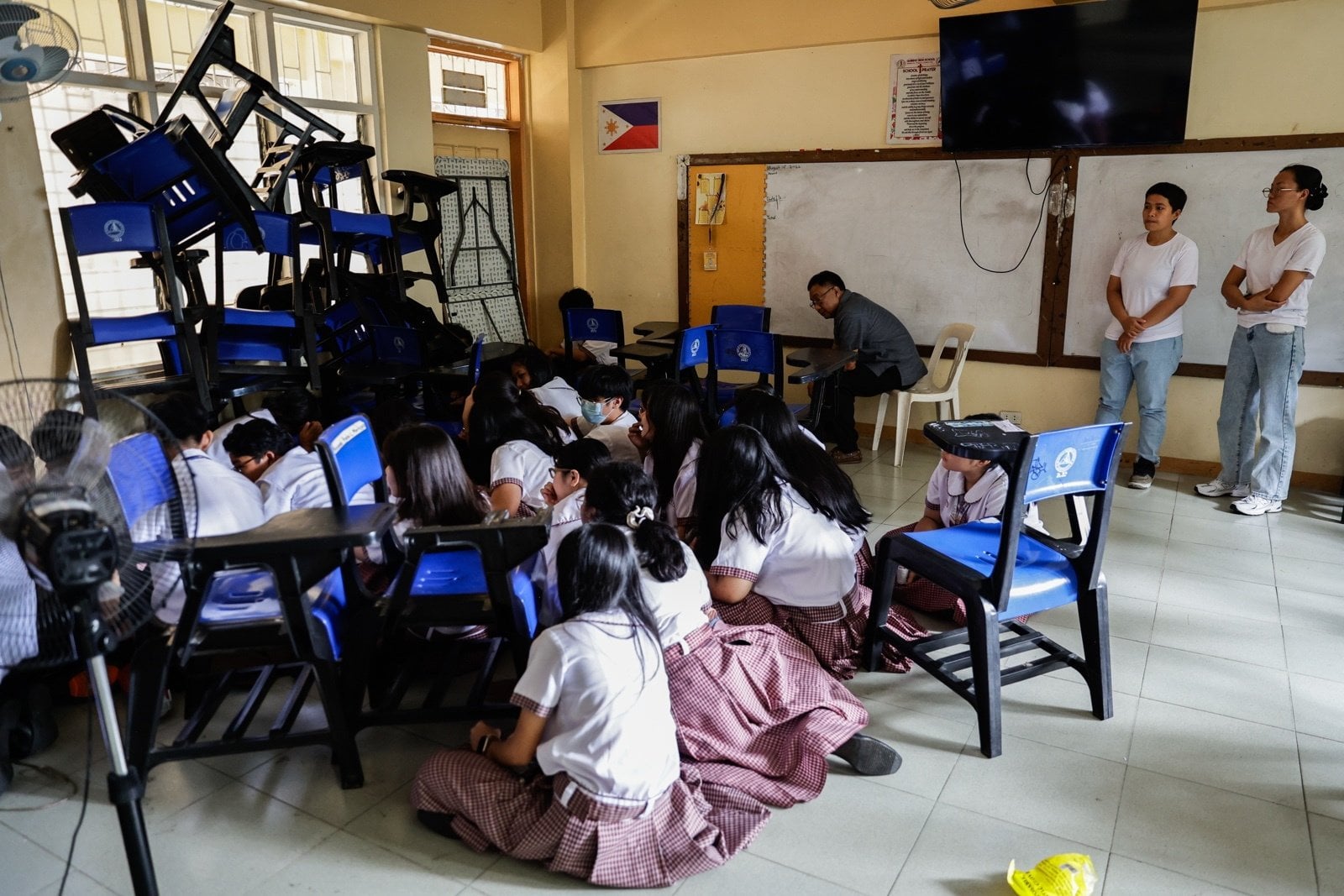 Philippine police (right) observe as students take safety positions with a teacher after barricading their classroom during a school safety drill in times of active attacks of violence, at a high school campus in Quezon City on Thursday. Photo: EPA