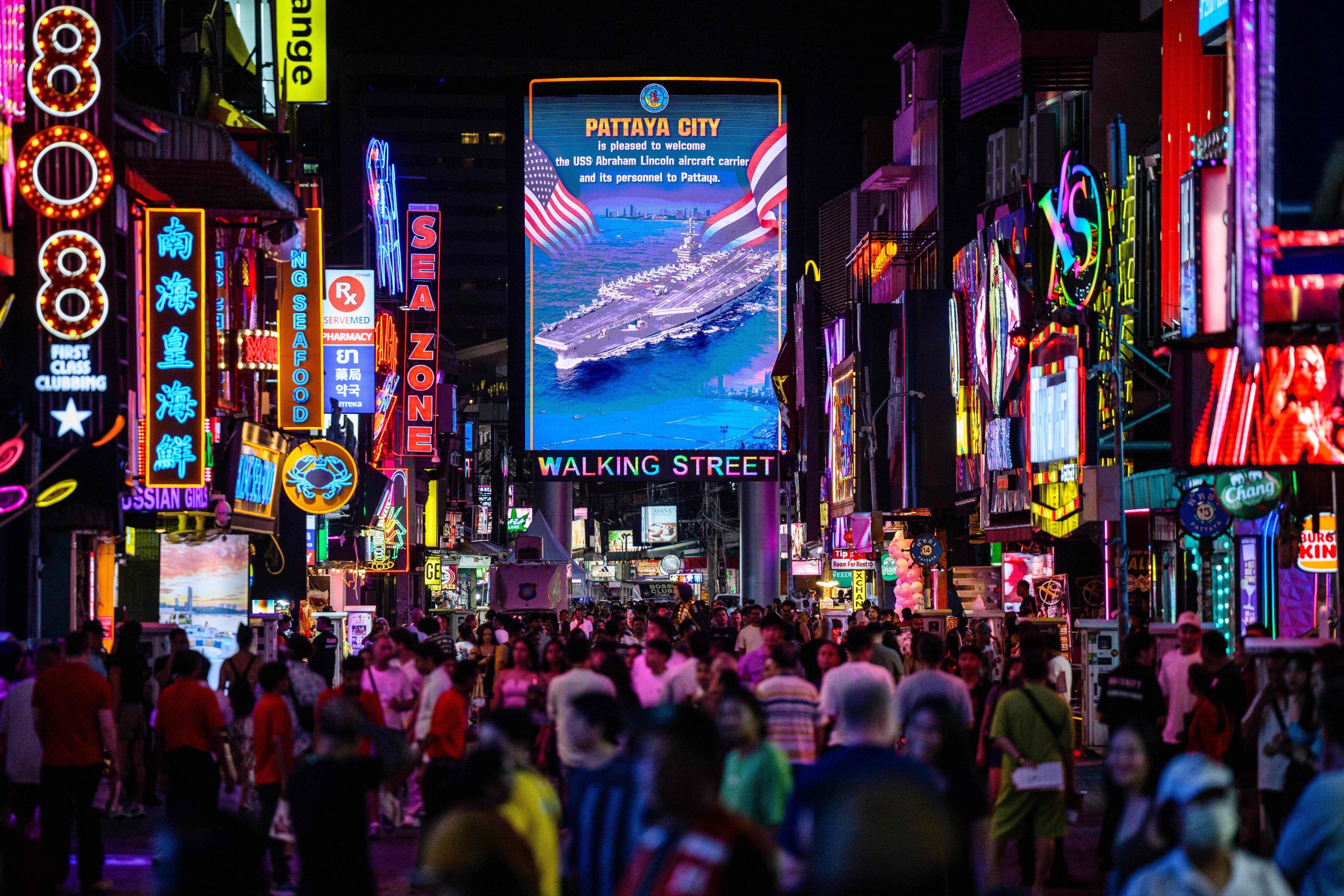 Pedestrians walk past a LED display welcoming the arrival of US service personnel of the USS Abraham Lincoln in Pattaya, Thailand, on Wednesday. Photo: AFP