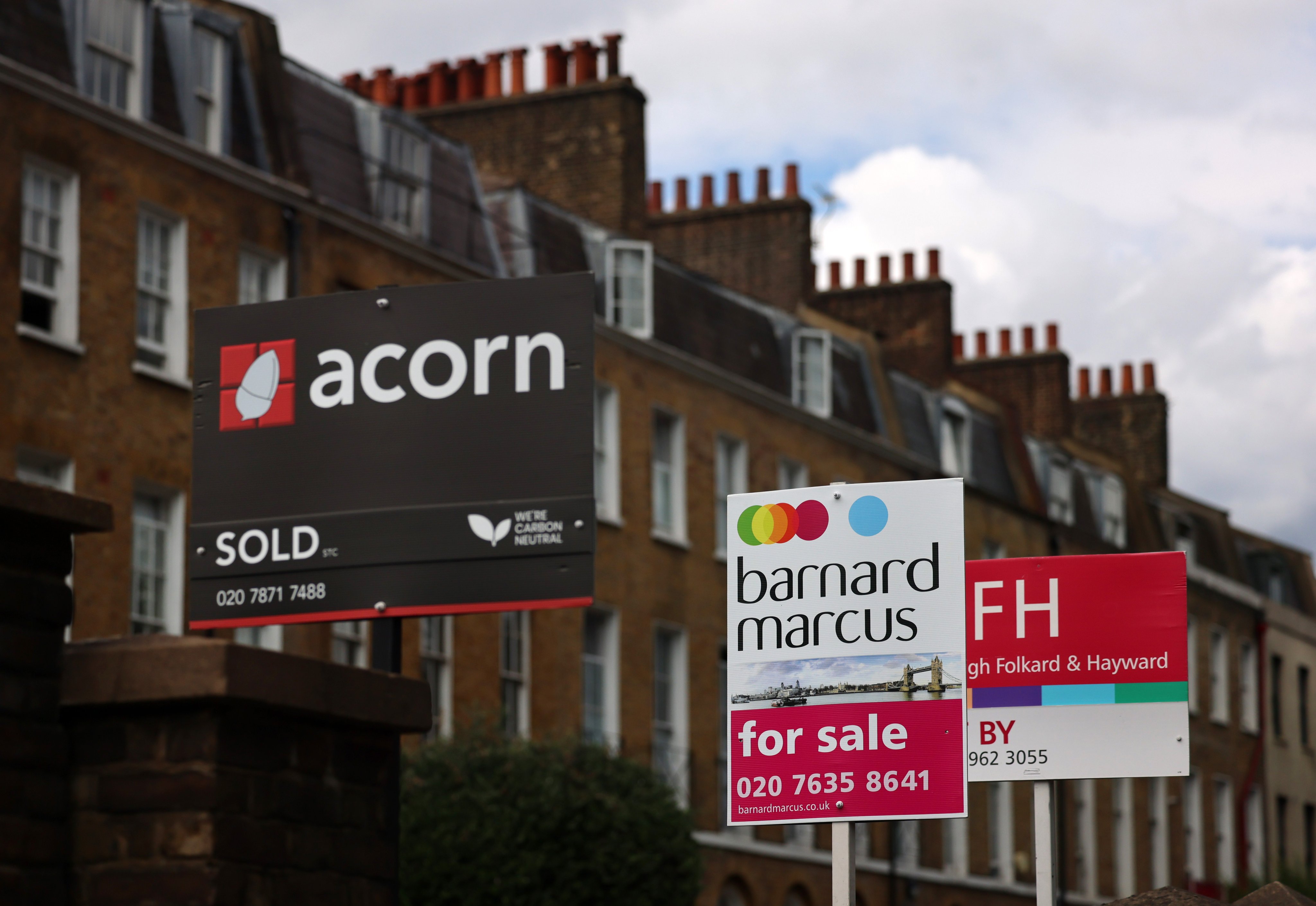 Real estate agents’ signs at a sold home and homes for sale in London last month. Photo: EPA
