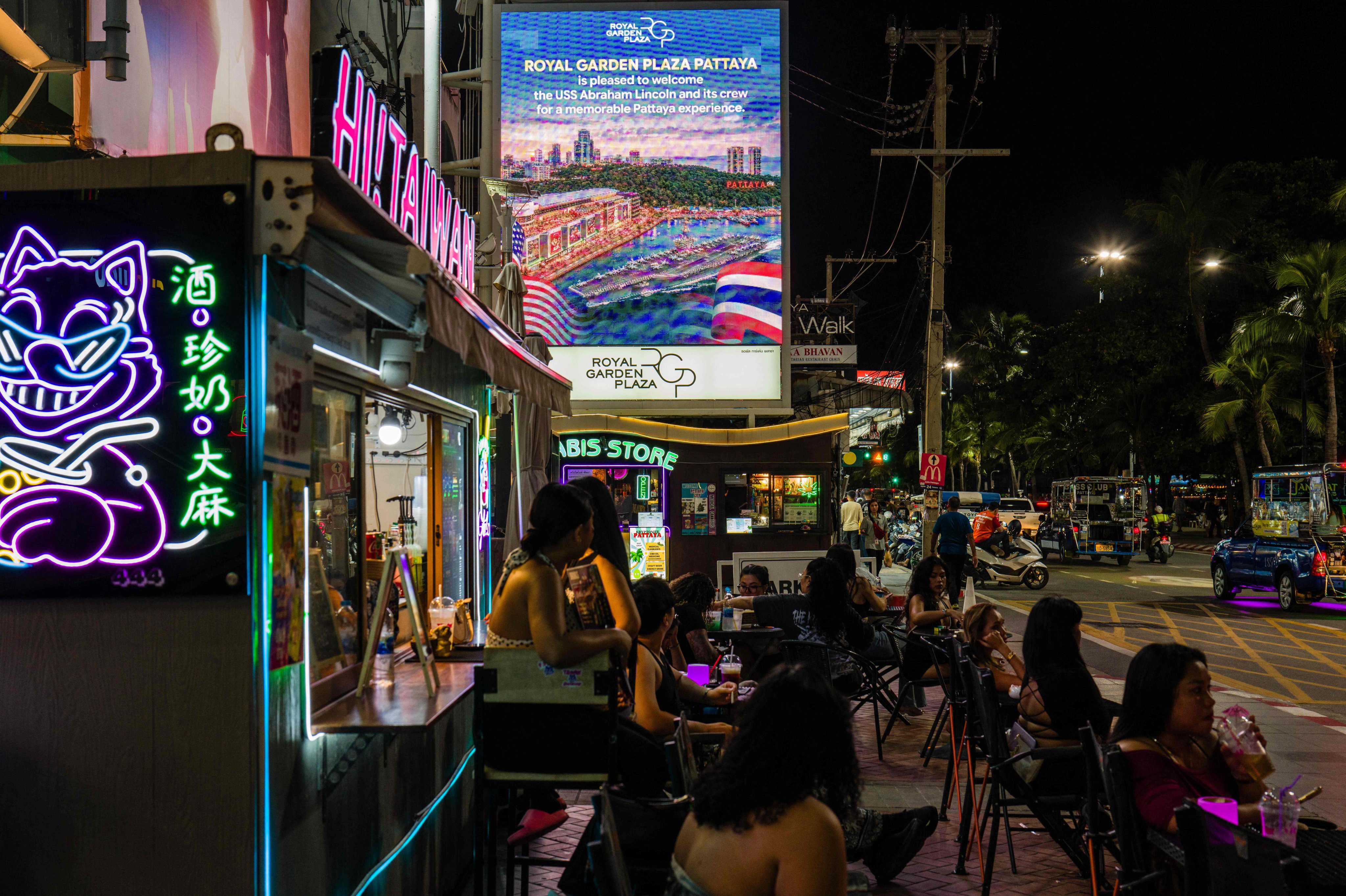 People sit near a large LED screen (top centre) welcoming the arrival of US service personnel of the USS Abraham Lincoln (CVN-72) in Pattaya on Wednesday. Photo: AFP