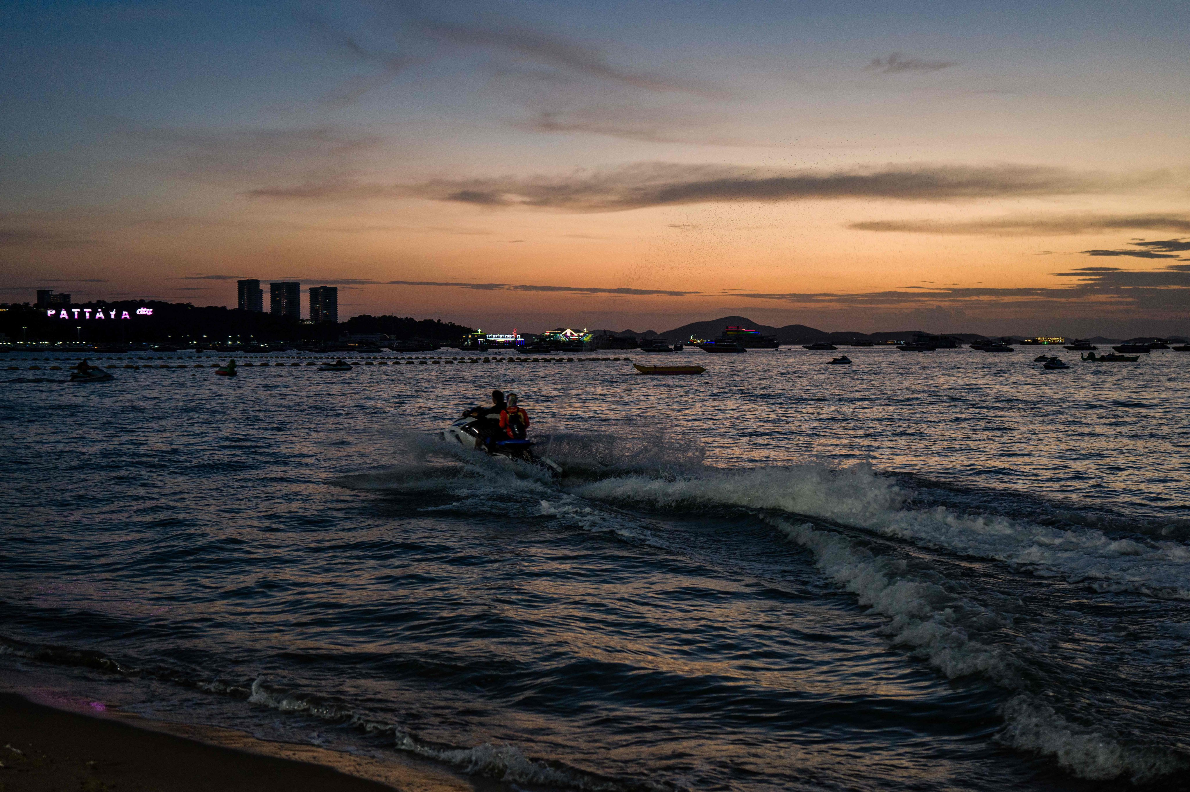 Visitor use a jet ski in the waters of Pattaya Beach in Thailand as the sun sets on Wednesday. Photo: AFP