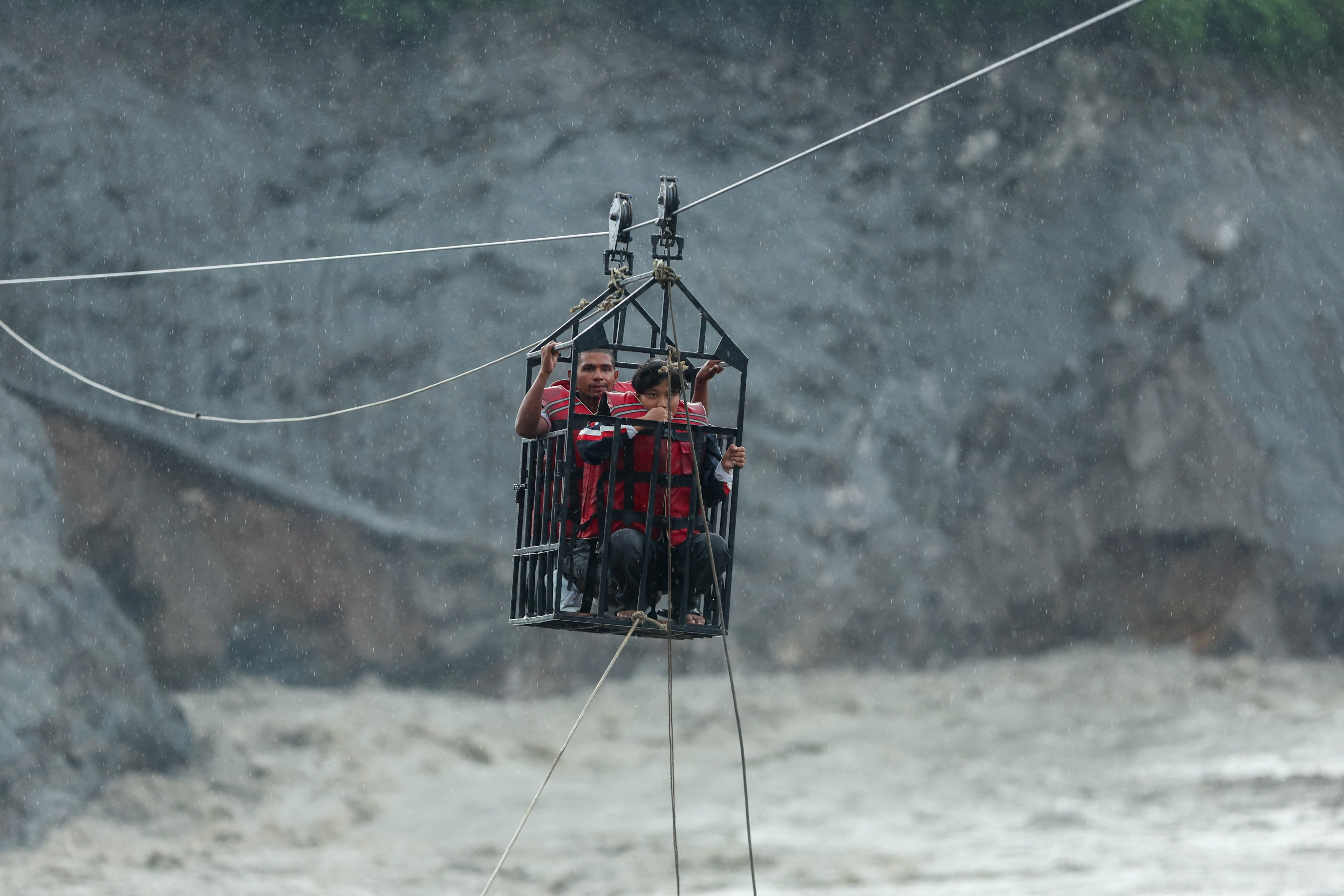 Nepalis ride in a cage on a makeshift zip line to cross the Trishuli River on Wednesday after landslides and mudslides damaged bridges in Nuwakot district, Nepal. Photo: Reuters