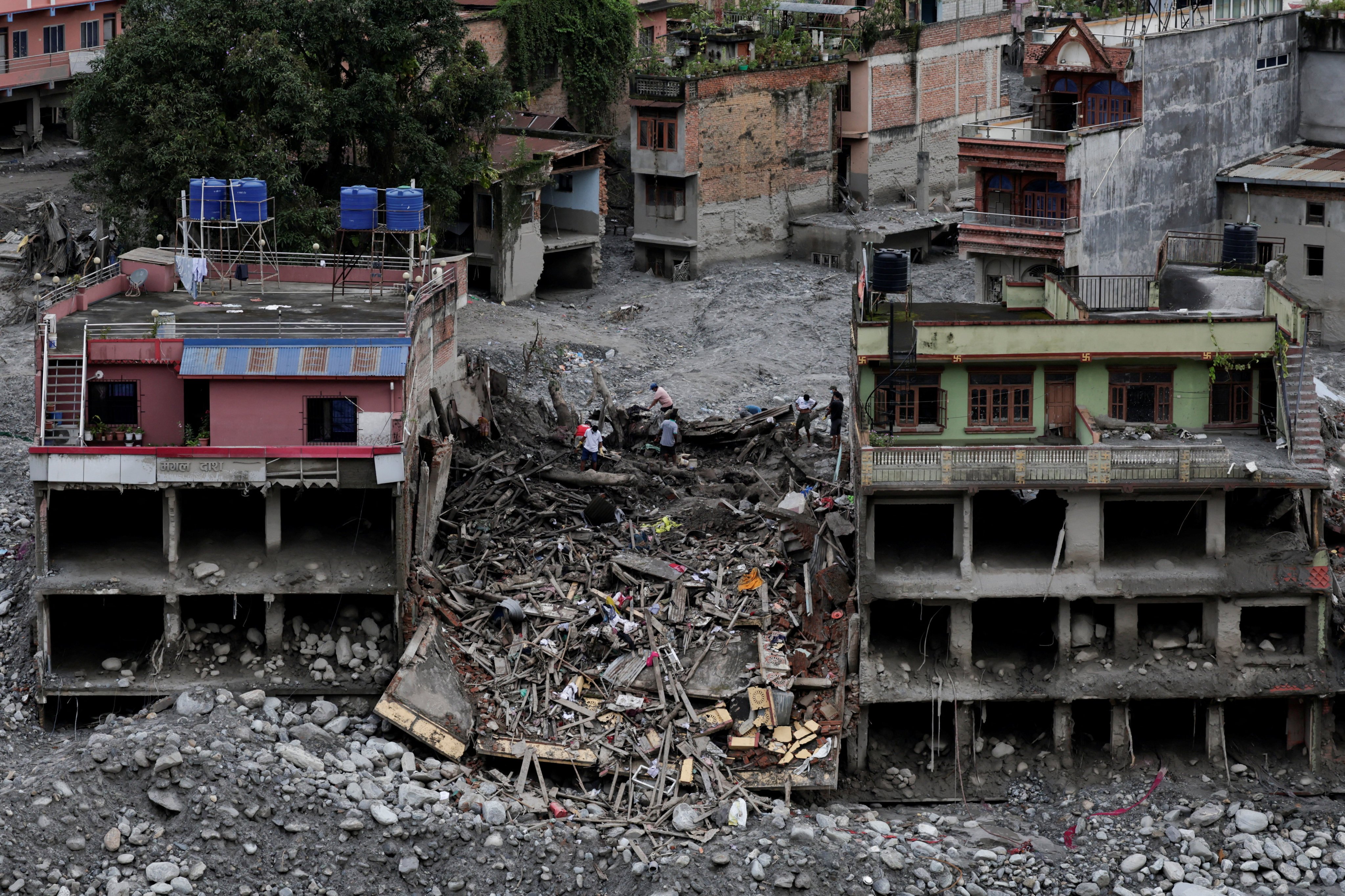 People in Nepal search for belongings on Saturday in the debris of a collapsed building following last week’s deadly flash floods. Photo: Reuters