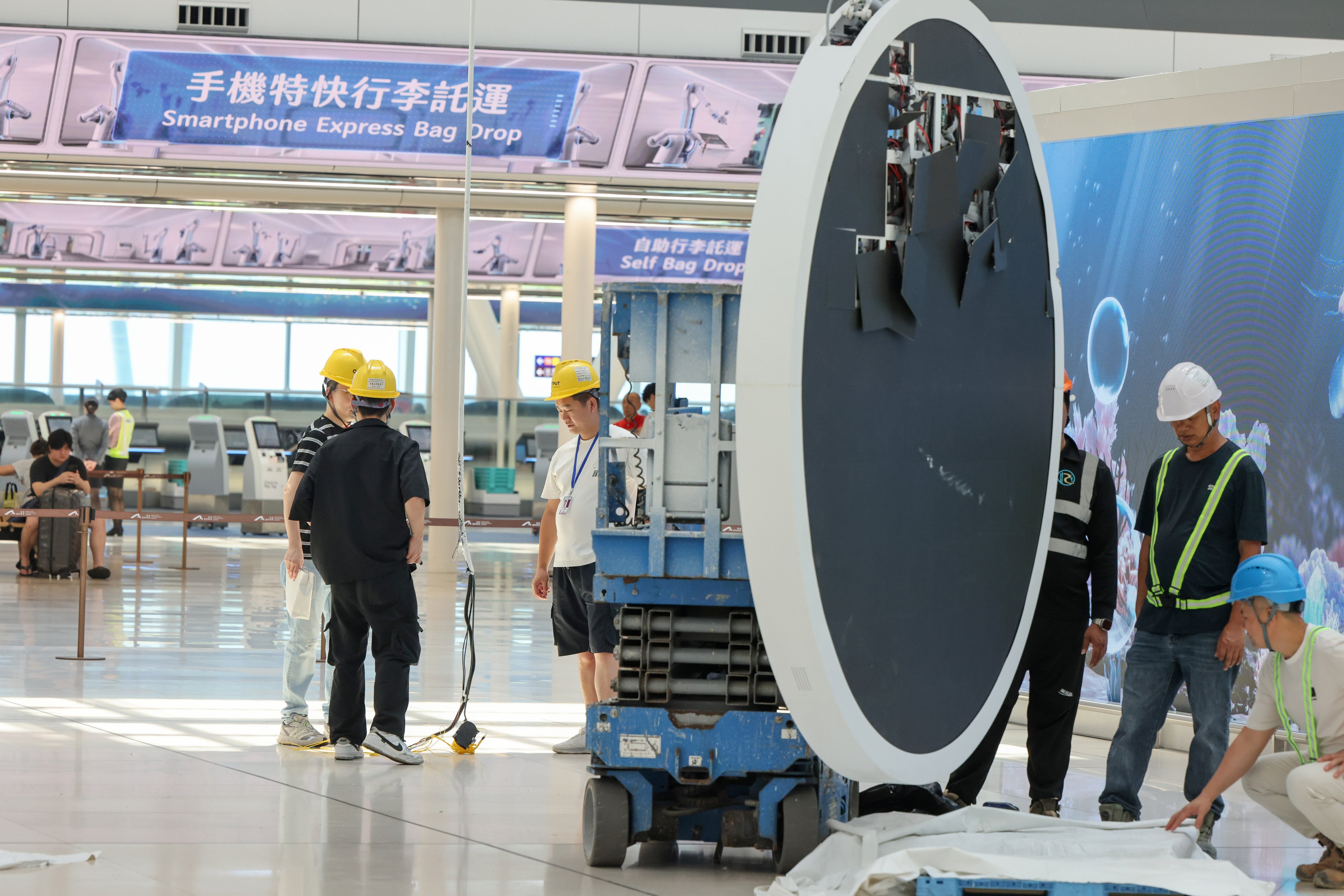 Engineers and workers examine an overhead monitor who was let loose in the air at the Hong Kong International Airport’s newly opened second terminal, with the Airport Authority saying it would investigate the incident in detail. Pictured at Hong Kong International Airport Terminal 2, Chek Lap Kok. 05SEP26 SCMP / Nora Tam