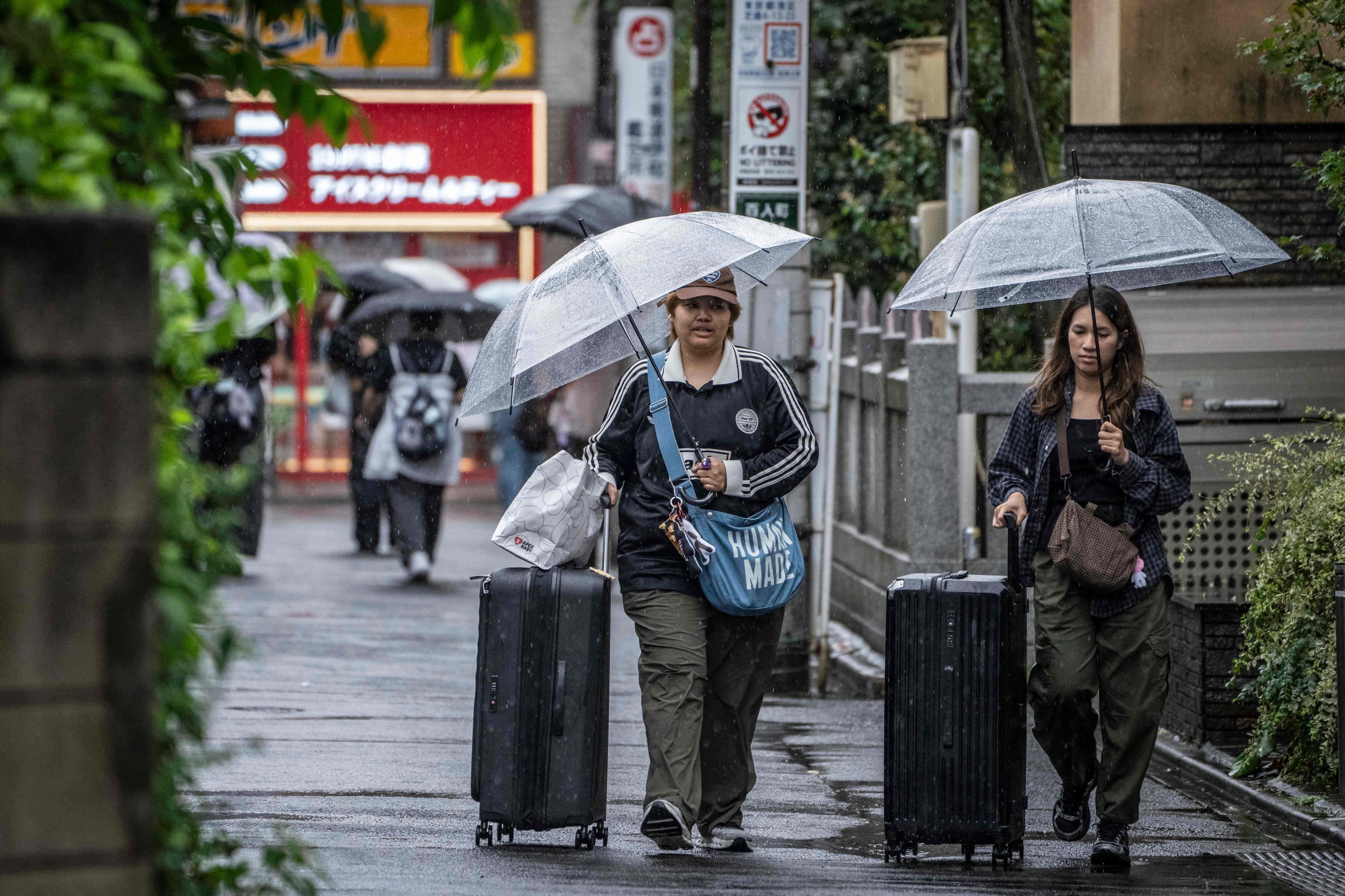 Foreign tourists pull their suitcases as they walk along a street near Shinjuku station in Tokyo on Monday. Photo: AFP