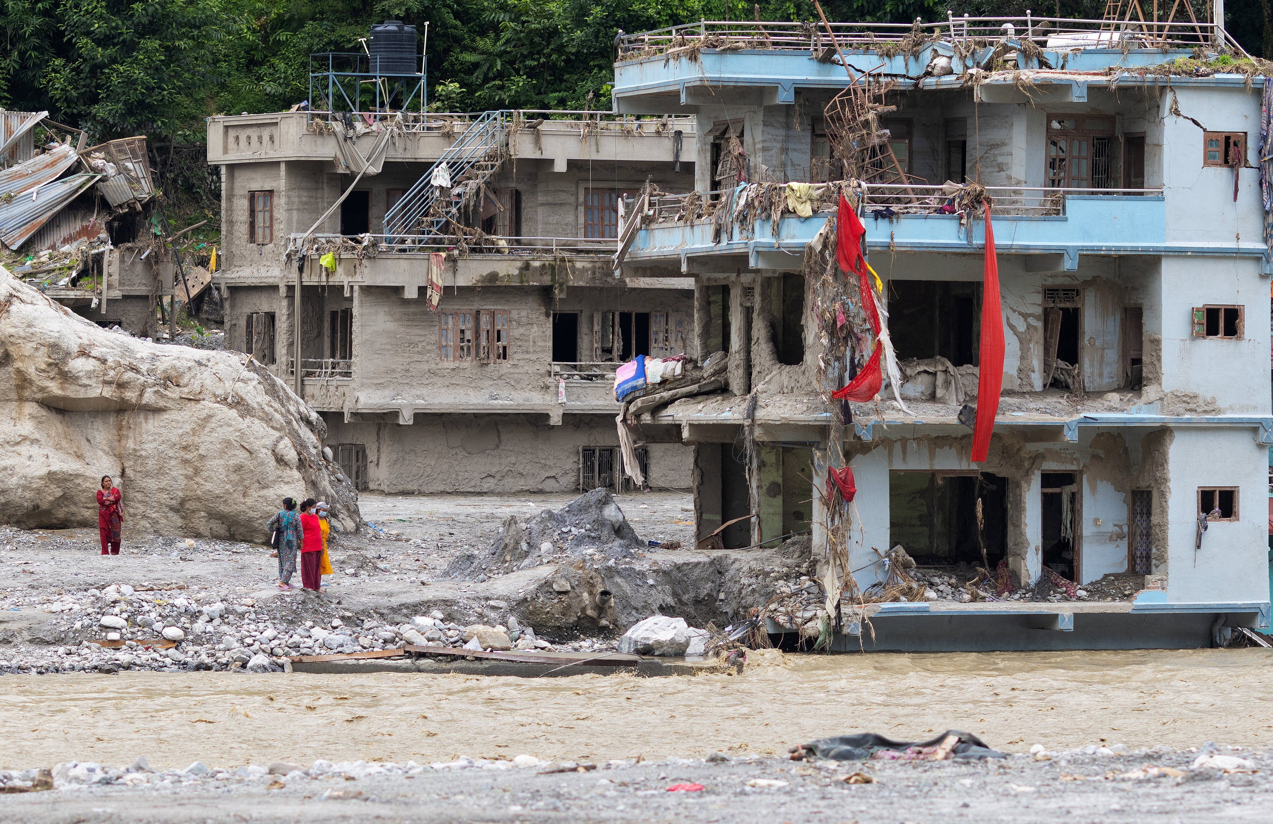 People stand next to damaged houses following the deadly flash floods and mudslides, in Betrawati, Nuwakot district, Nepal, on Sunday. Photo: Reuters