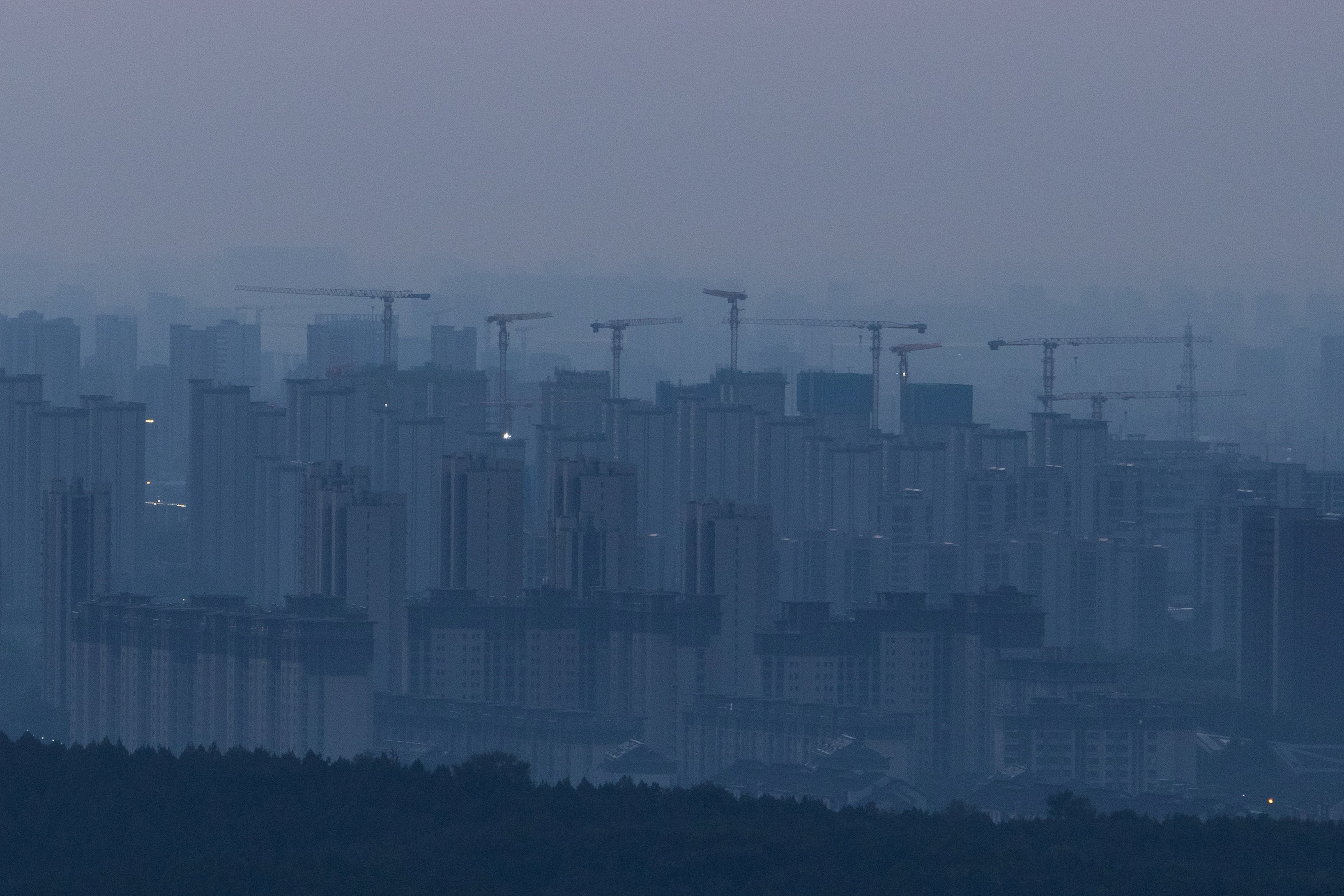 Construction cranes rise above a newly built residential district before sunrise in Beijing on September 3. Photo: Reuters
