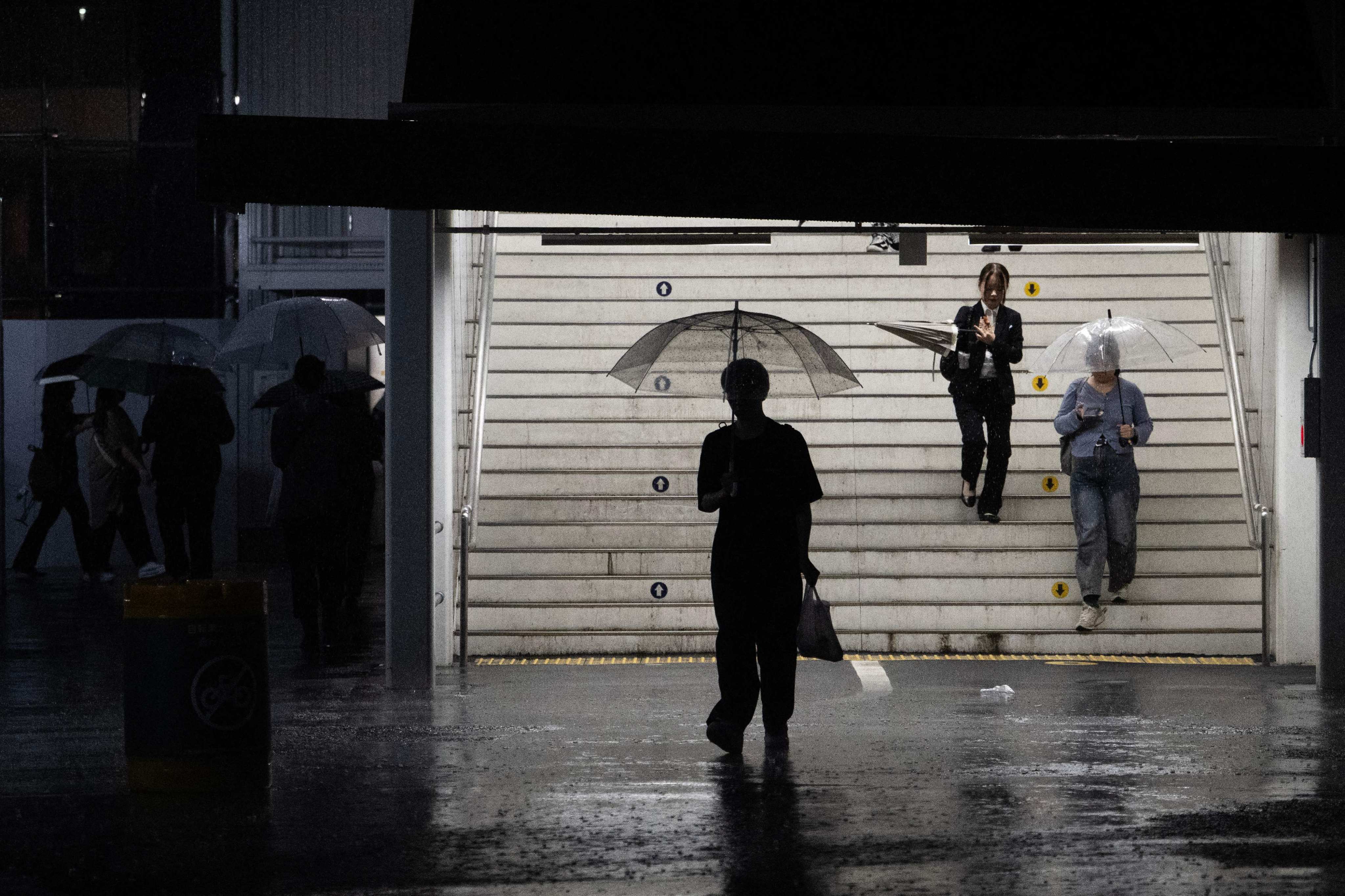 Commuters exit a train station during a heavy rainstorm in Tokyo on Sunday. Photo: AFP