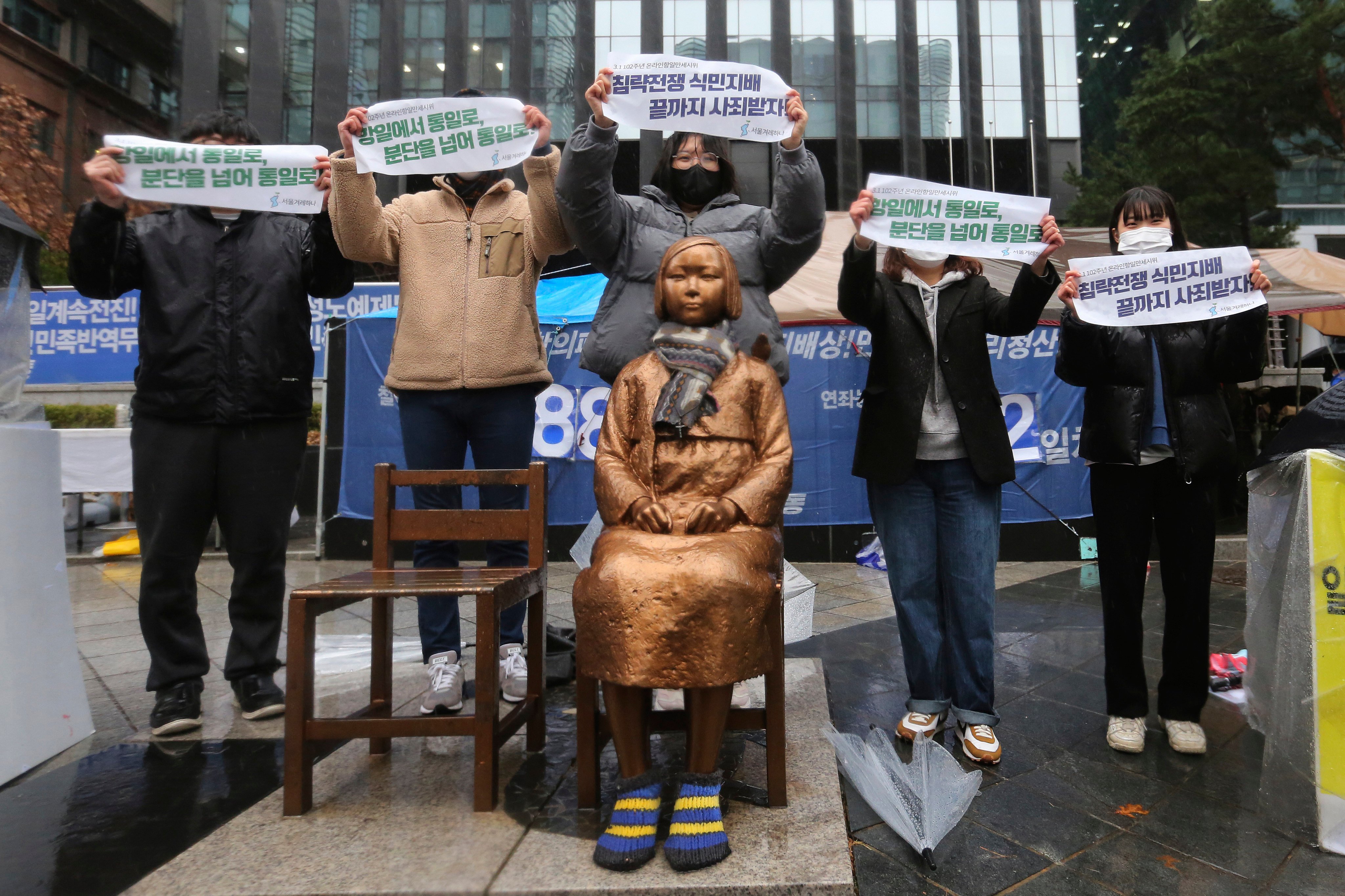 Protesters hold up banners during a rally against Japanese colonial rule, in front of a statue symbolising a wartime sex slave near the Japanese embassy in Seoul, in 2021. Photo: AP