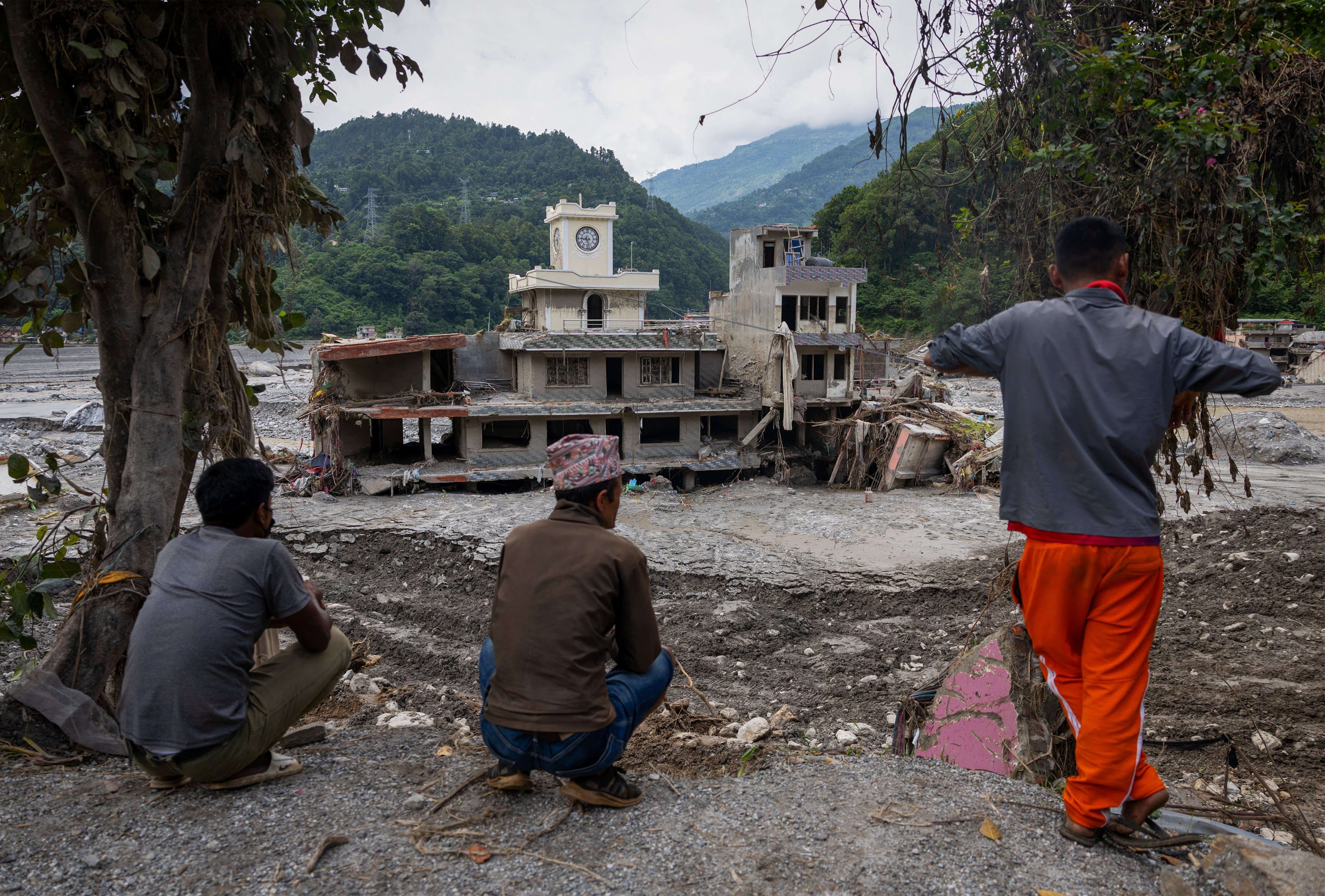 People sit on a hill near damaged houses following the deadly flash floods and mudslides, in Betrawati, Nuwakot district, Nepal, on Sunday. Photo: Reuters