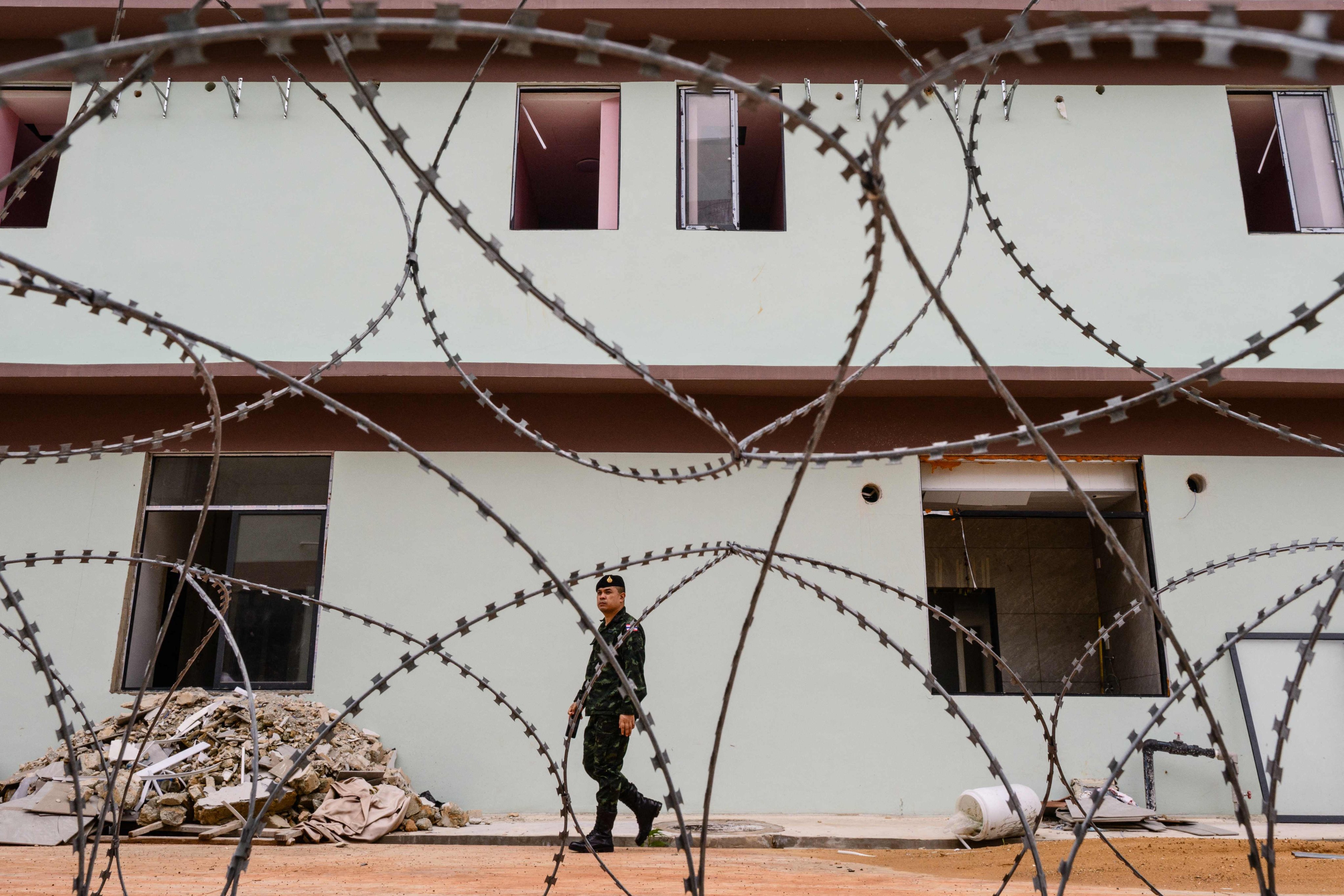 A Royal Thai Army soldier walks beyond barbed wire outside hospital buildings of an abandoned scam centre in O’Smach town on the Thai-Cambodian border, on Monday. Photo: AFP