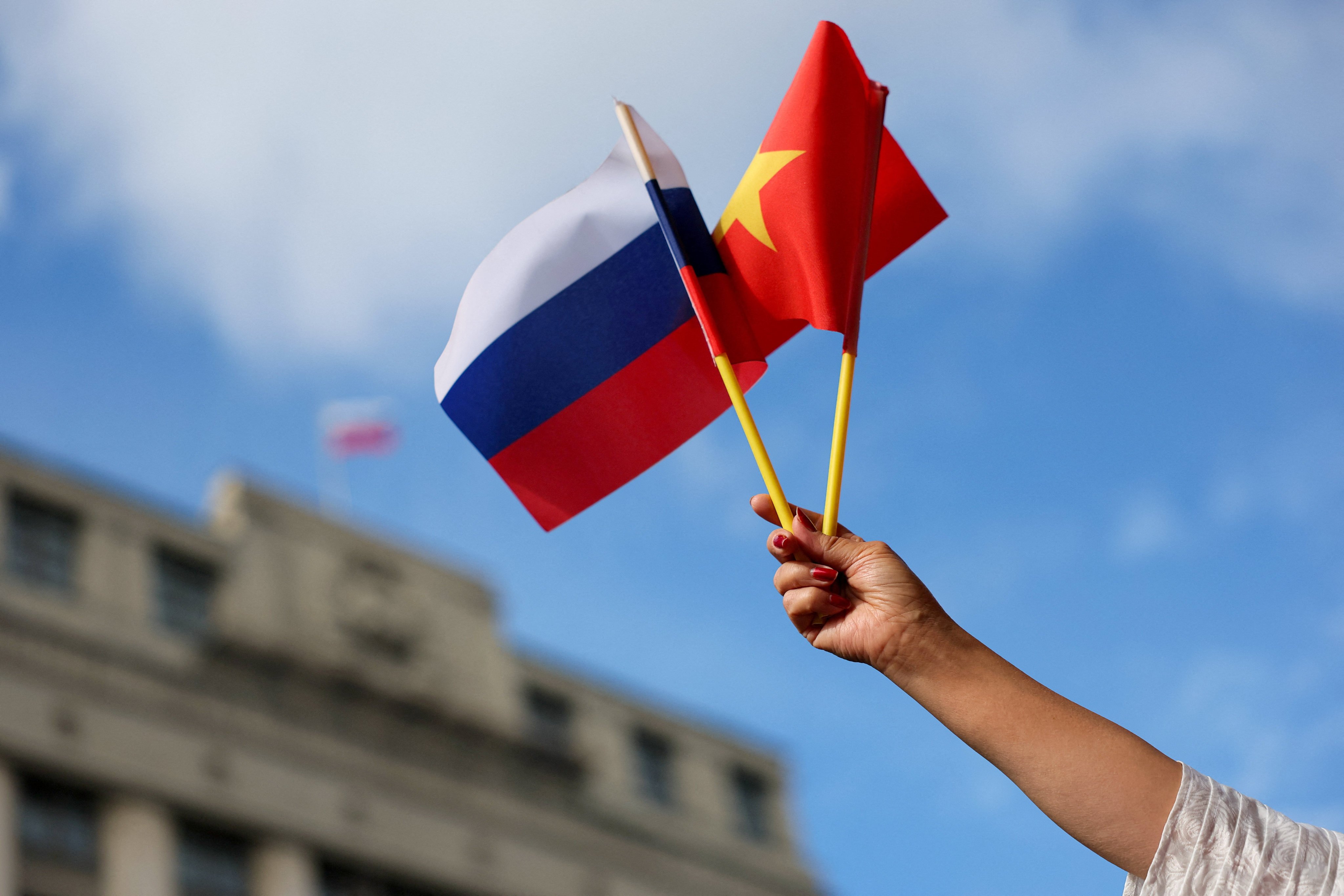 A member of a welcoming delegation for To Lam waves flags in front of the headquarters of Russia’s lower house of parliament on Monday. Photo: Reuters
