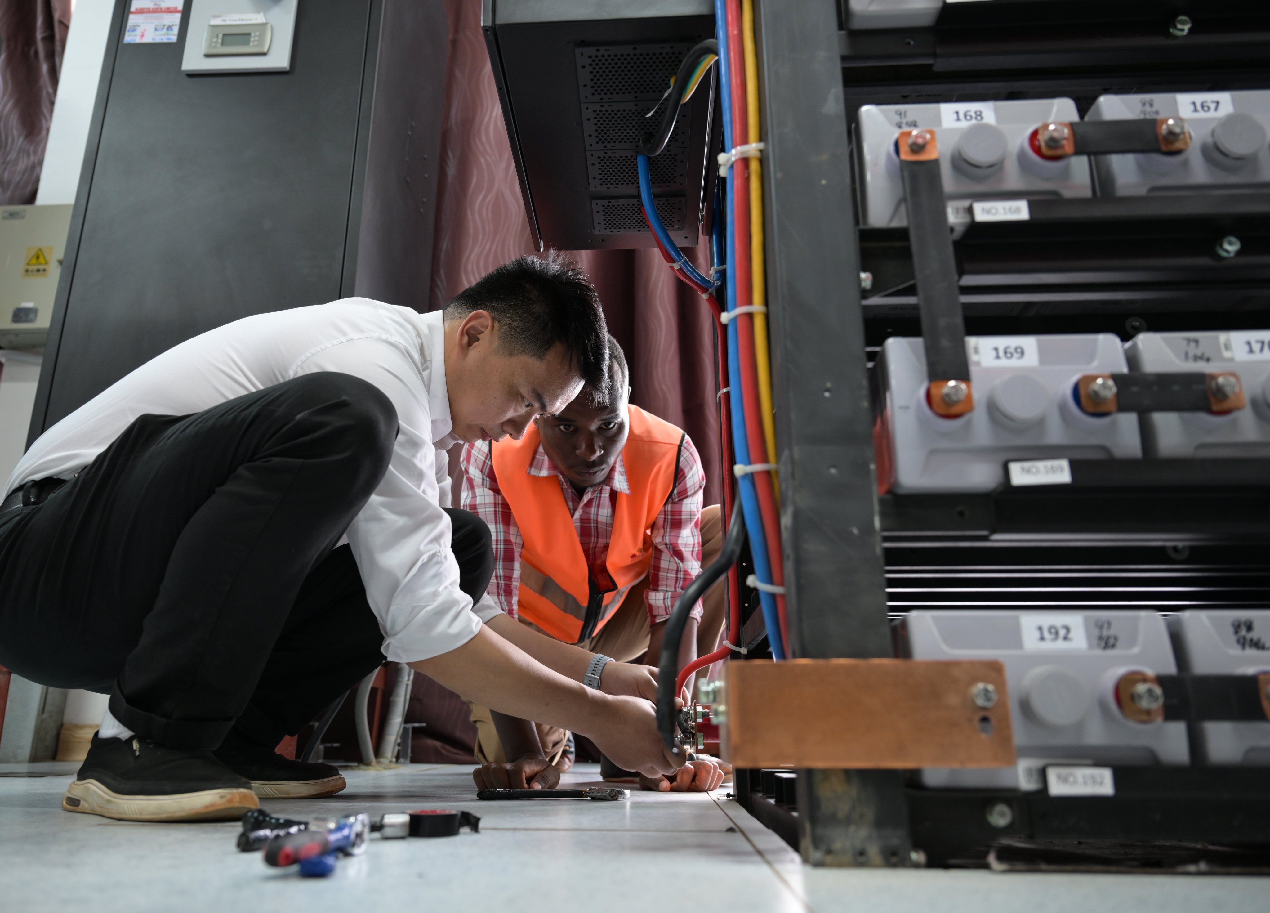 A Chinese communication engineer guides a Kenyan staff member on backup power replacement for the communication system at Mtito Andei station on the Mombasa-Nairobi Standard Gauge Railway in Kenya on July 23. The railway is part of China’s Belt and Road Initiaitve. Photo: Xinhua