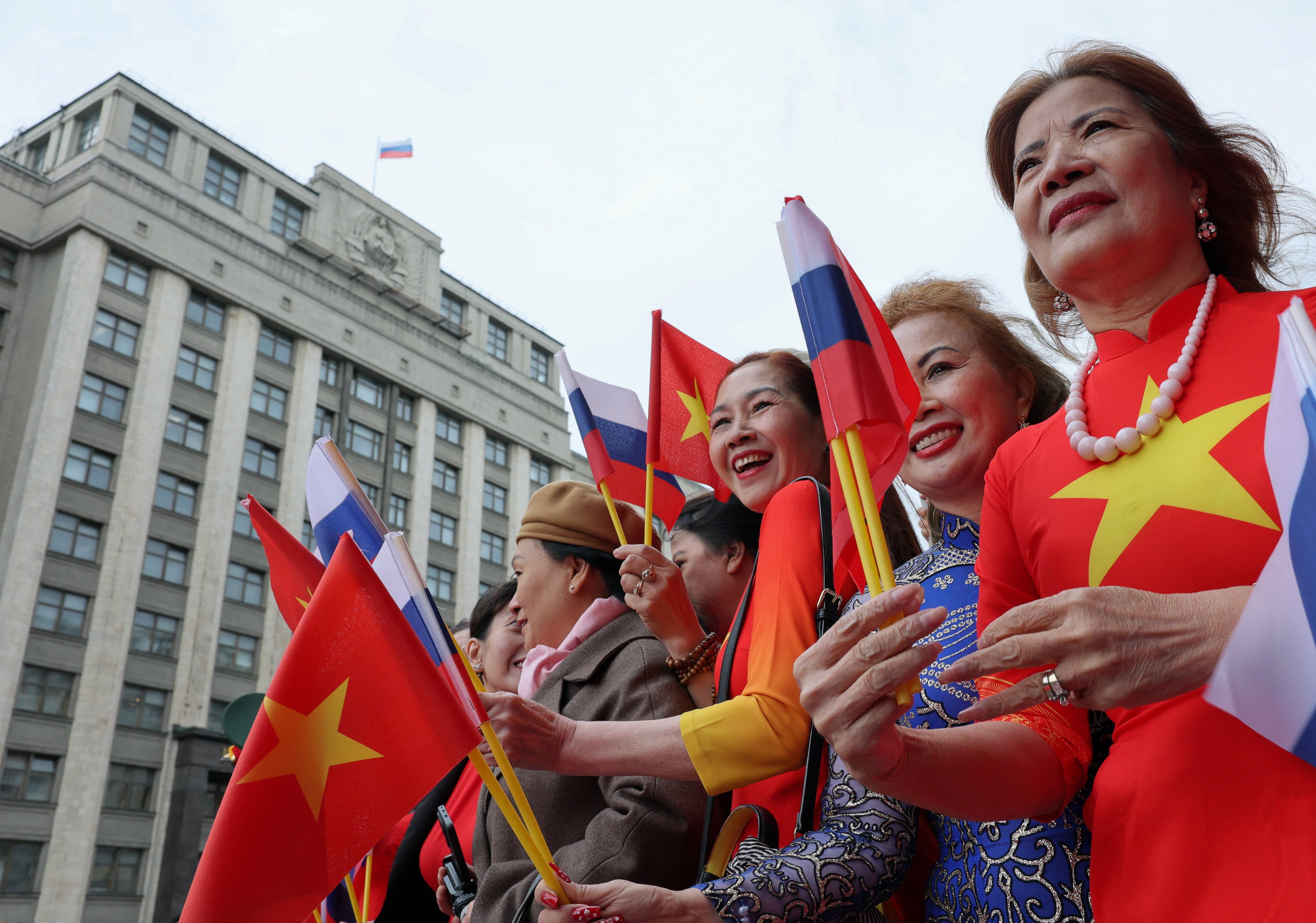 Members of the welcoming delegation for To Lam hold flags in front of the headquarters of Russia’s lower house of parliament on Monday. Photo: Reuters