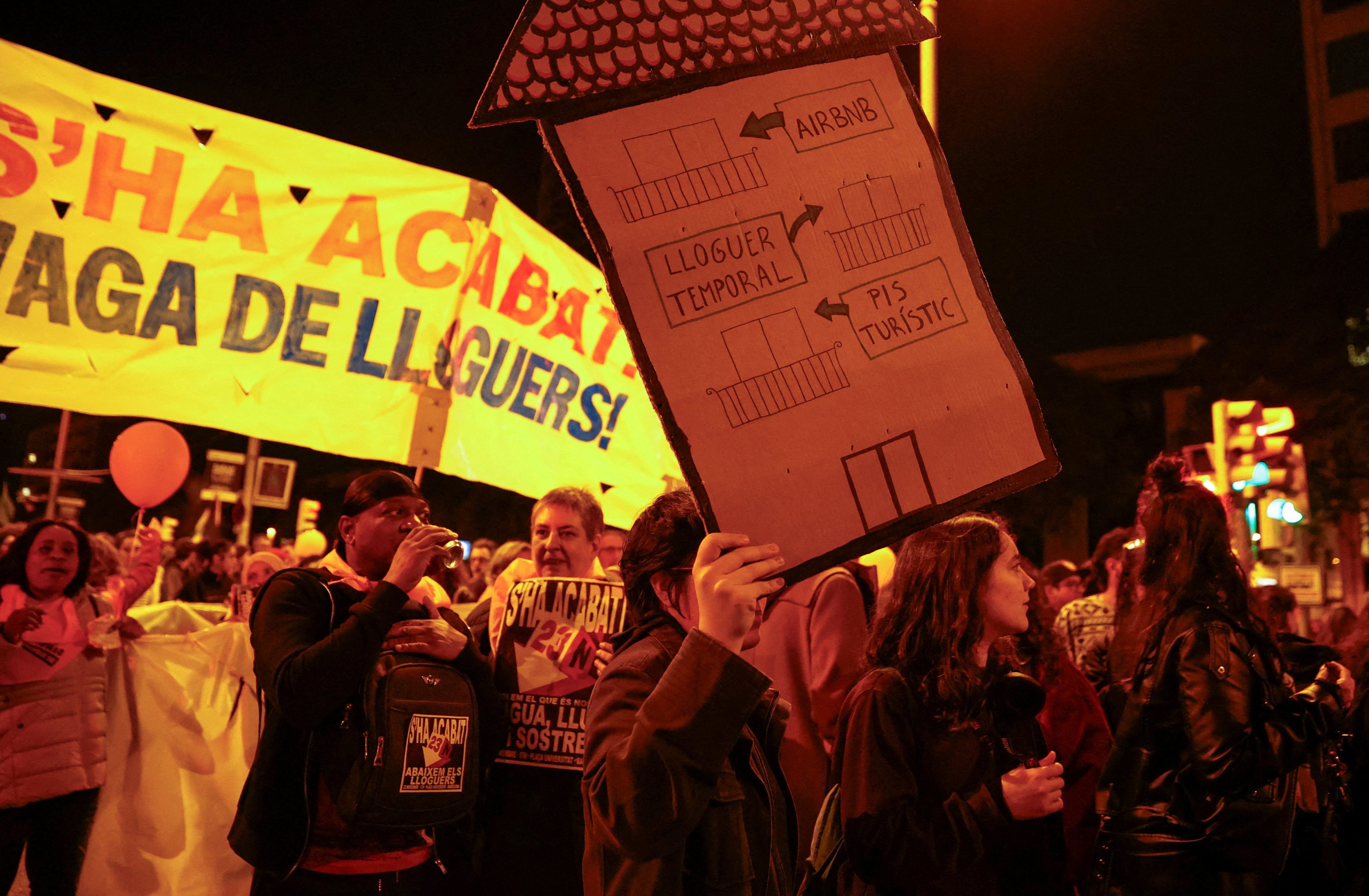A person holds a sign that reads “from touristic flat to temporary rent to Airbnb” during a protest to demand lower housing rental prices and better living conditions, in Barcelona, Spain, in November 2024. Photo: Reuters