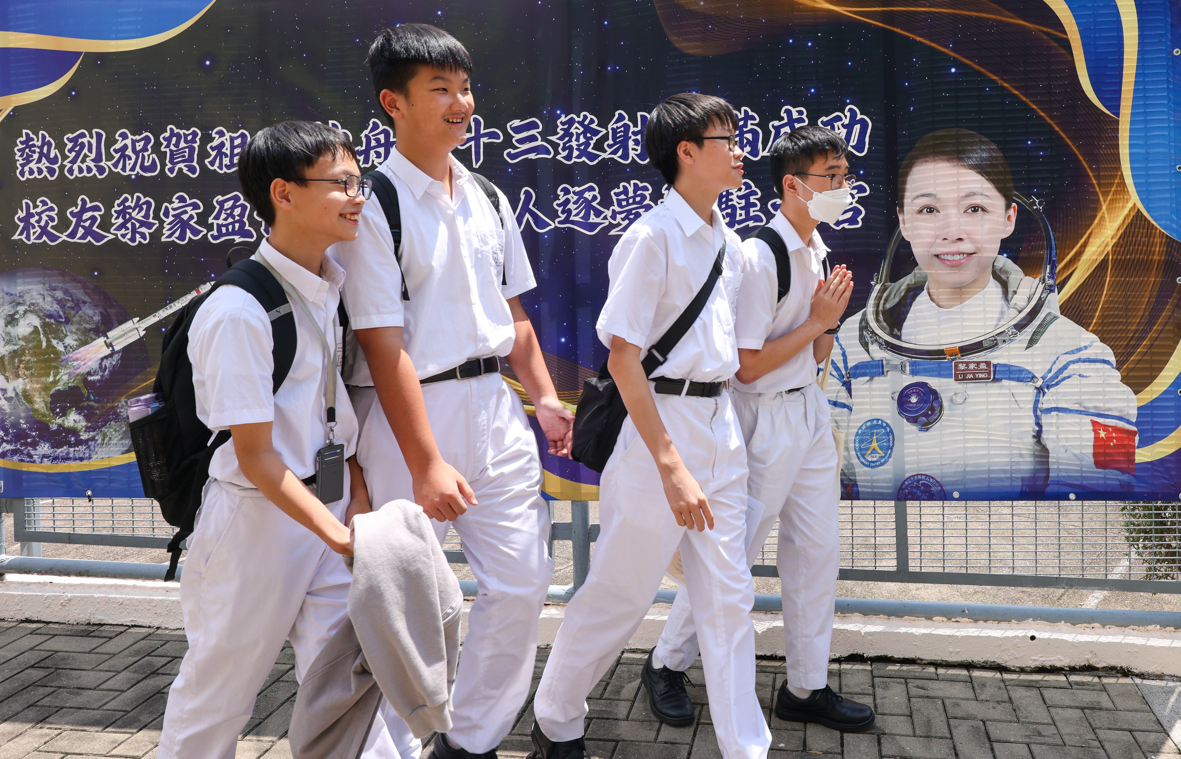 Students of Tsuen Wan Public Ho Chuen Yiu Memorial College, the alma mater of Lai Ka-ying, walk past a poster for the Hong Kong astronaut’s “Tiangong Class” on Wednesday. Photo: Nora Tam