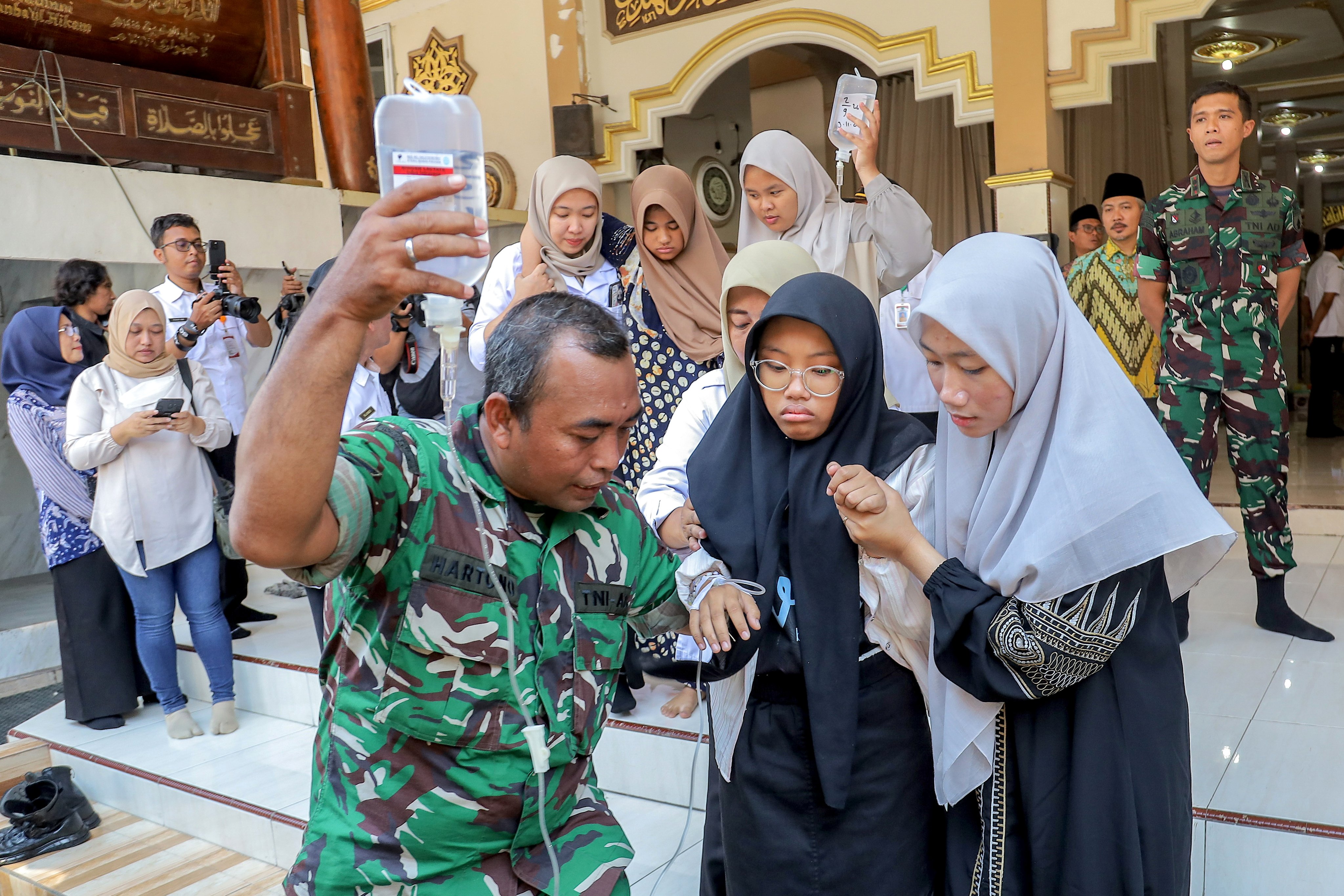 Paramedics guide students suffering from food poisoning to receive medical treatment at the Manbaul Hikam Islamic boarding school in Sidoarjo, East Java, on September 2. Photo: EPA