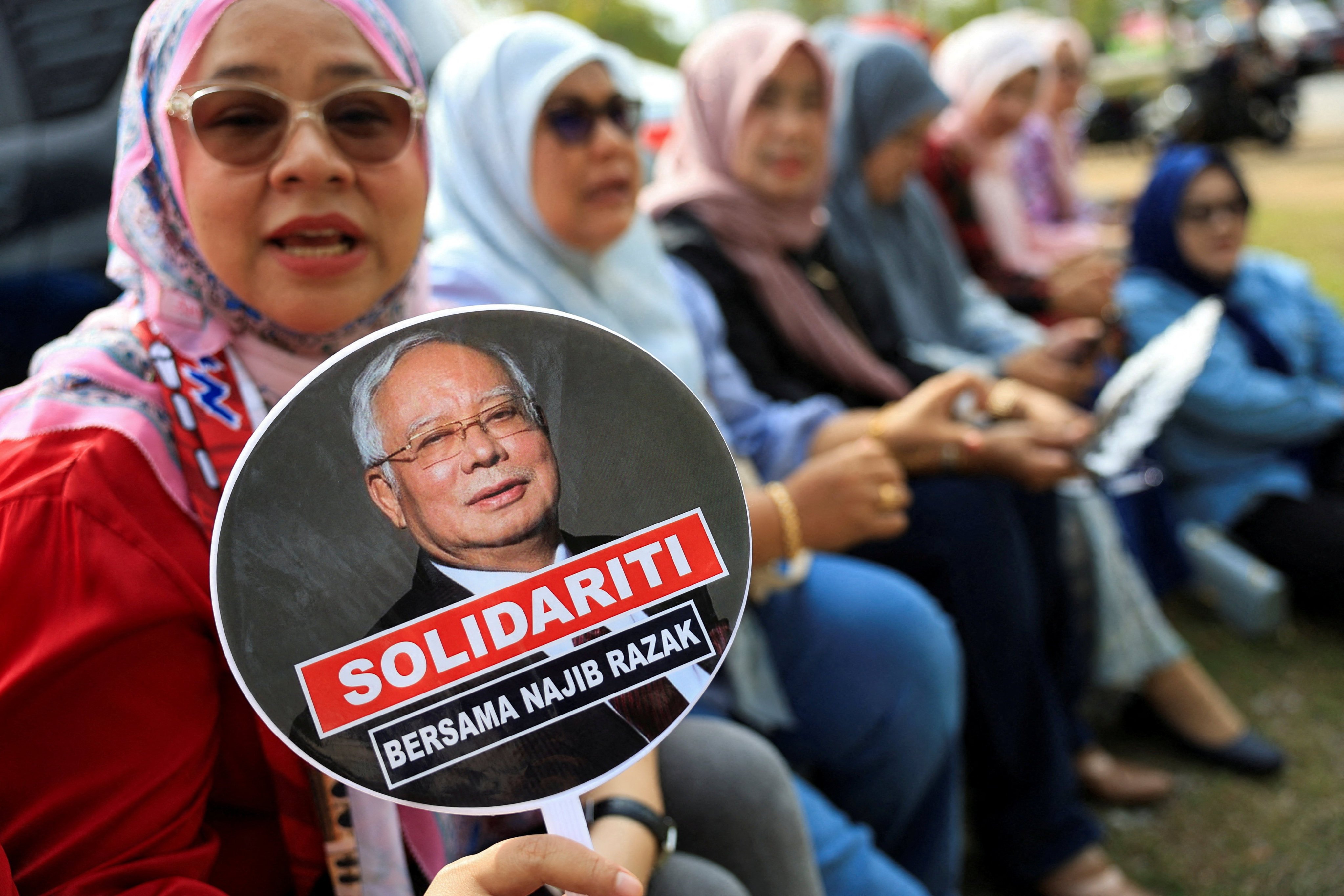 A supporter of former Malaysian prime minister Najib Razak holds a hand fan with a picture of Najib printed on it, outside the federal court in Putrajaya last year. Photo: Reuters
