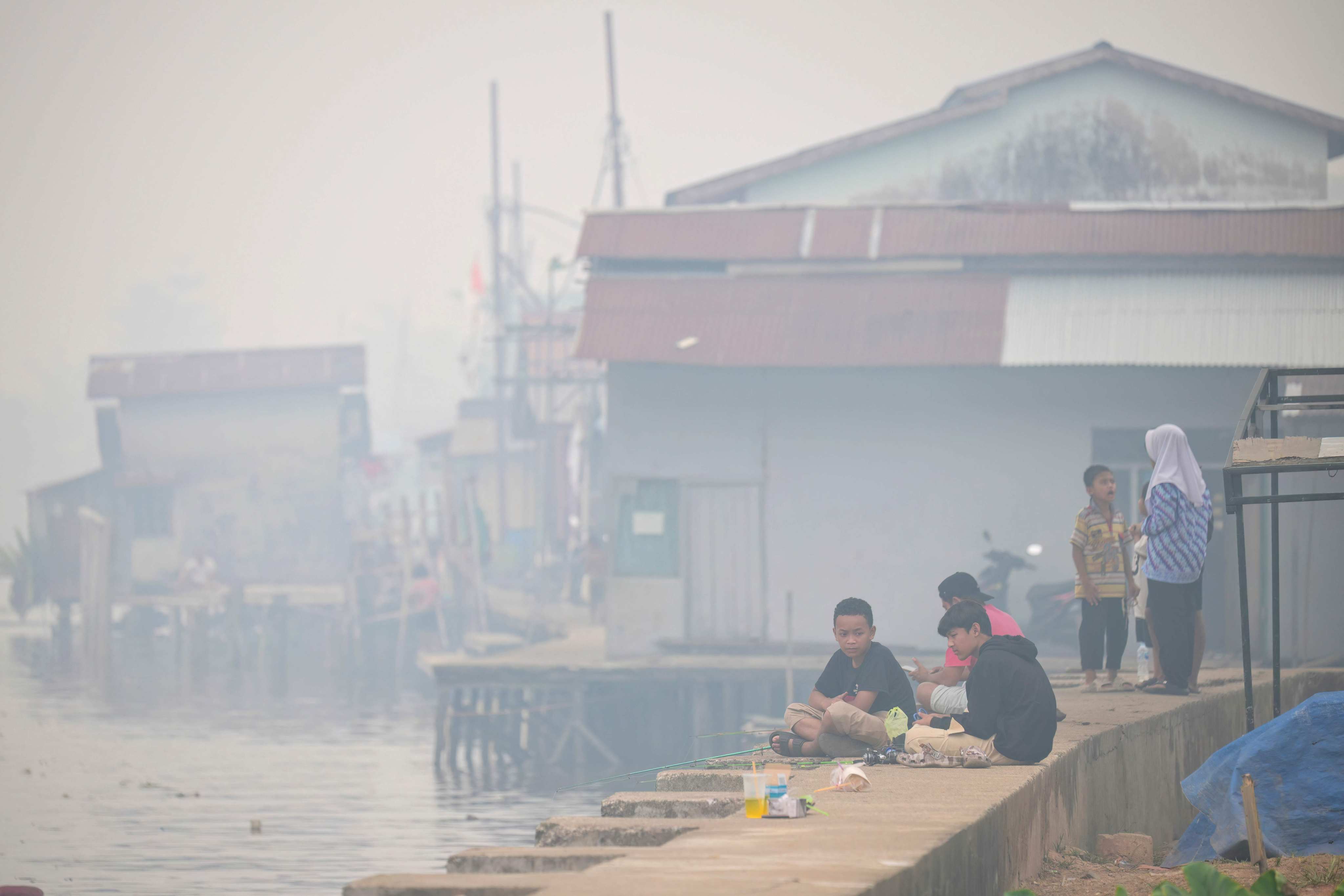 Residents gather by the banks of the Kapuas river as thick smoke and haze shrouds the city of Pontianak in West Kalimantan, Indonesia, on Sunday. Photo: AFP