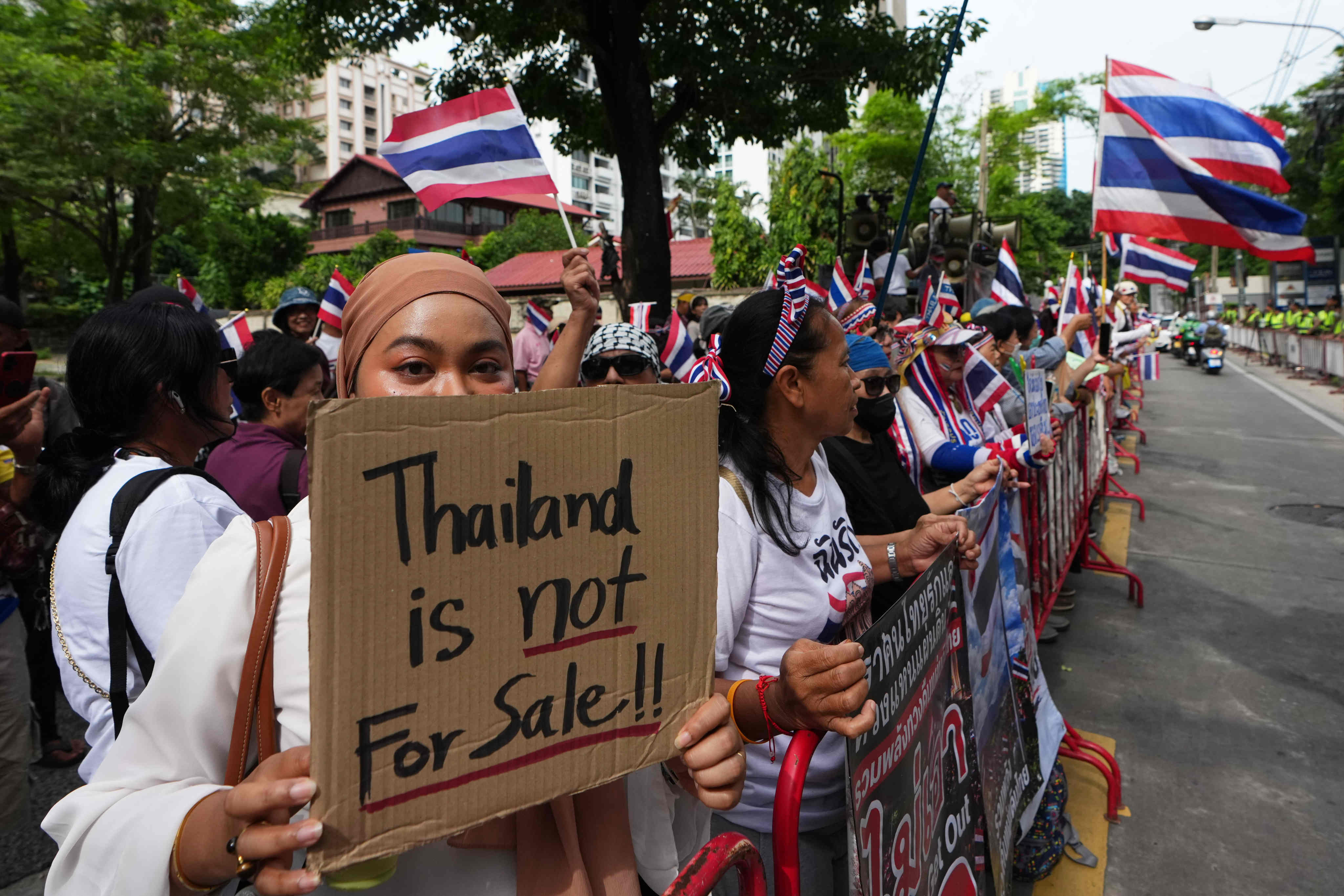 Protesters holding signs attend a rally demanding an end to alleged land-grabbing by foreigners in Bangkok on Thursday. Photo: AP