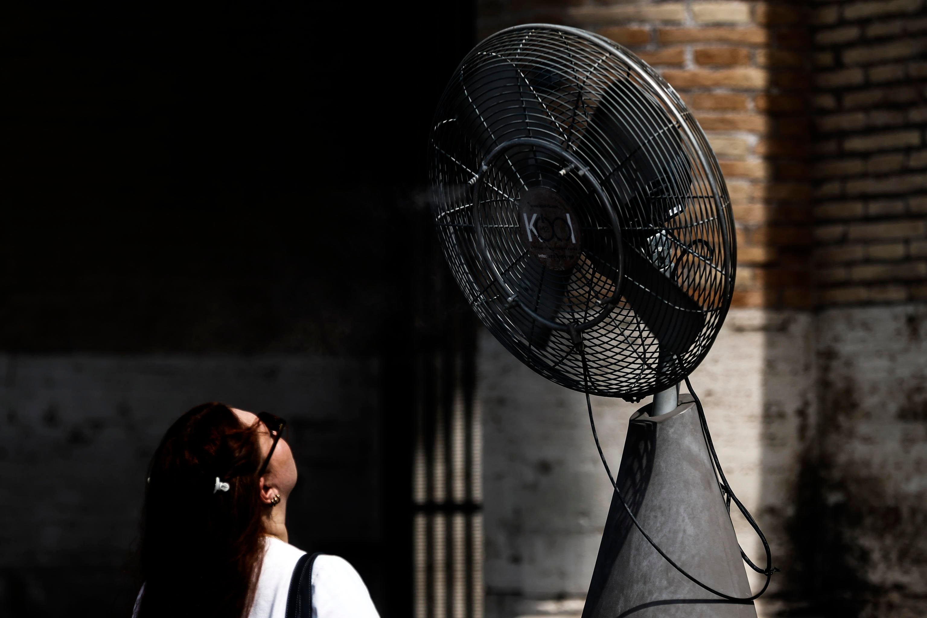 A person cools off in front of a fan in the Colosseum in Rome, Italy. Photo: EPA