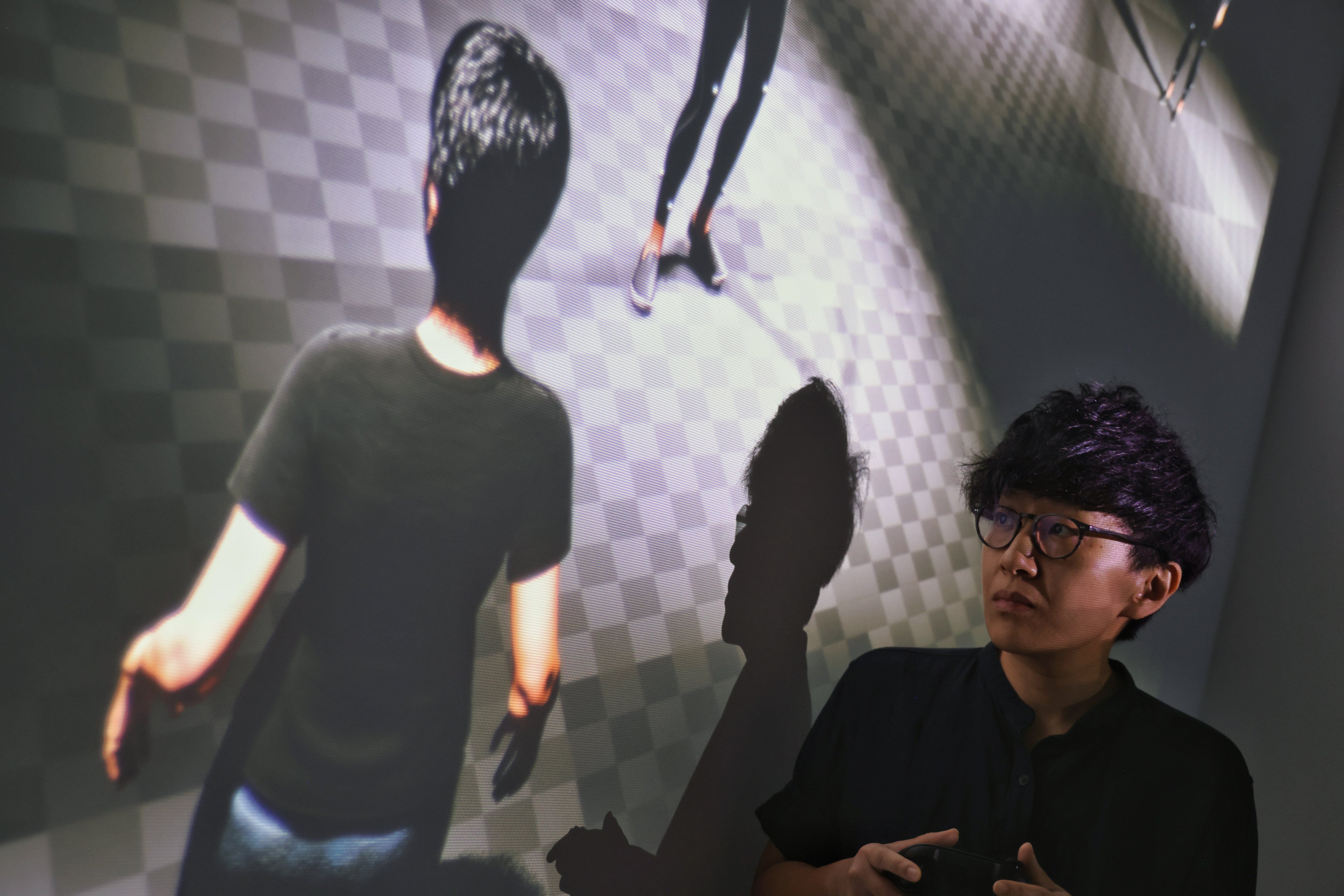 Lau plays their video game Duplicate.exe (2026), in which the player controls the artist’s digital avatar W.A.I., at the “After Intelligence” exhibition at De Sarthe. Photo: Silvia Siu