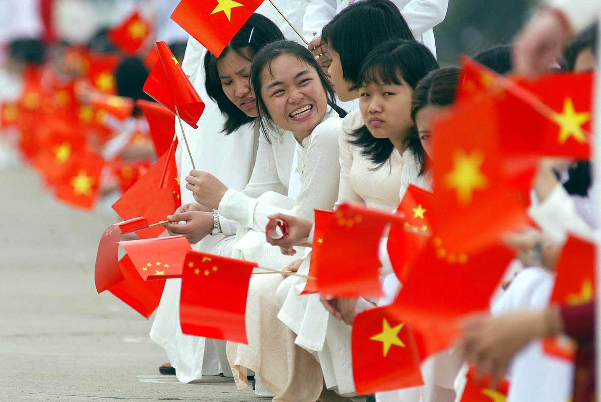 Young Vietnamese women in Hanoi wave Chinese and Vietnamese flags ahead of state visit by China's president in 2001. Photo: AFP