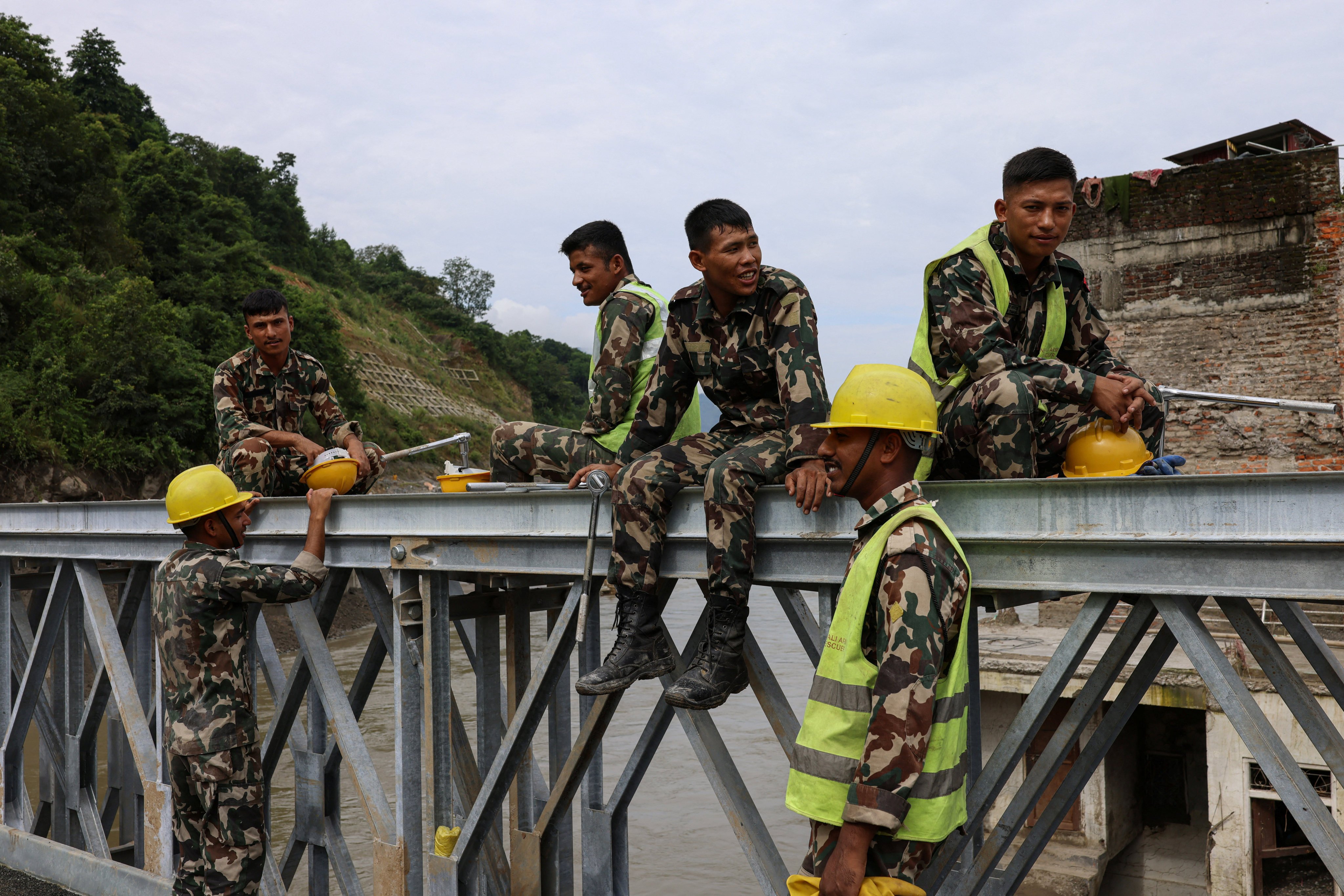 Nepalese Army personnel rest on a newly opened iron bridge, following deadly flash floods and a mudslide, in Devighat, Nuwakot district, Nepal, September 10, 2026. REUTERS/Tyrone Siu