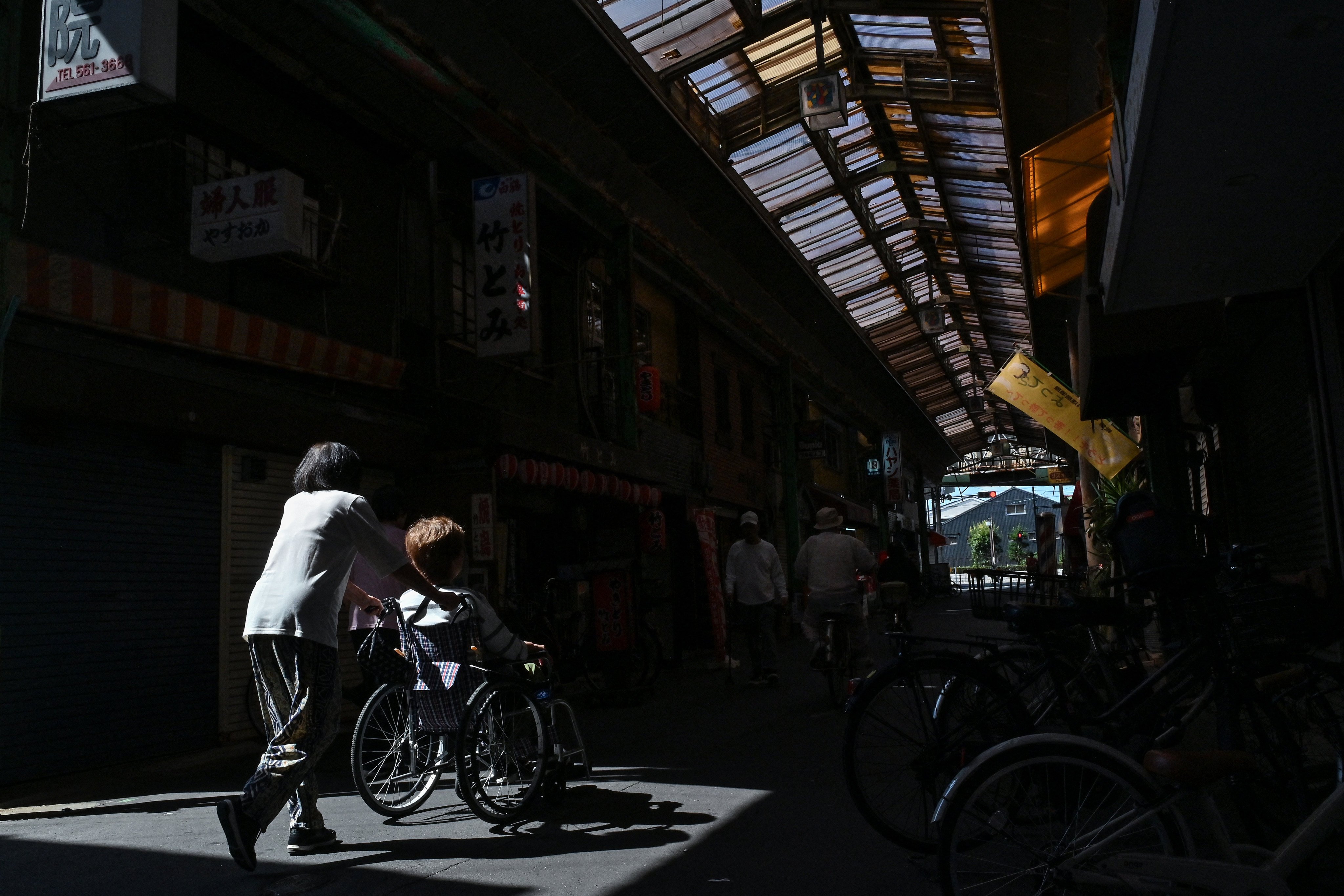 An elderly woman is pushed through the an old covered shopping street in Osaka. Japan had 67,871 foreign nationals employed in its skilled nursing-care category as of late 2025. Photo: AFP