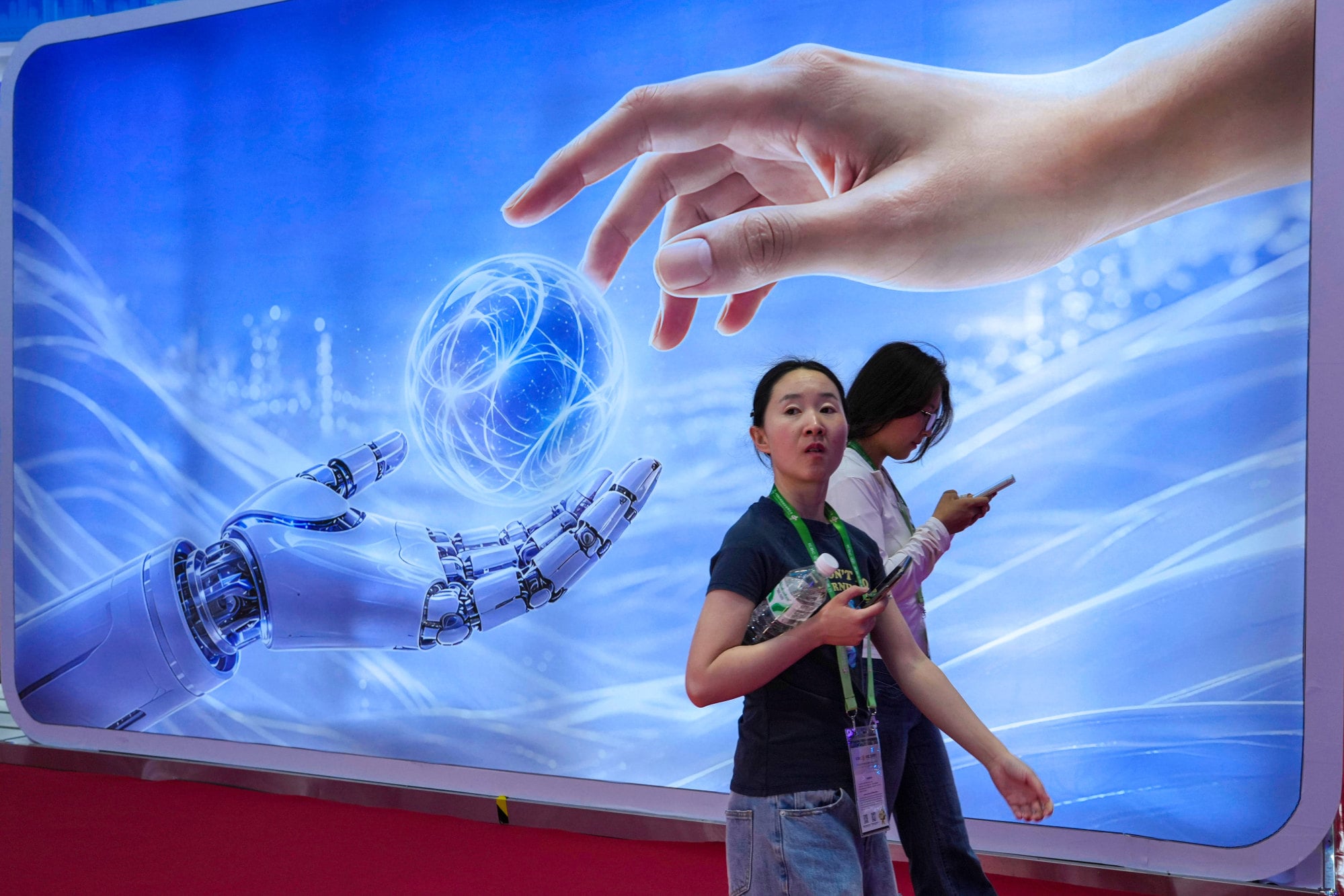 Visitors walk past a display depicting artificial intelligence and a human hand at the China International Supply Chain Expo in Beijing on June 22, 2026. Photo: AP