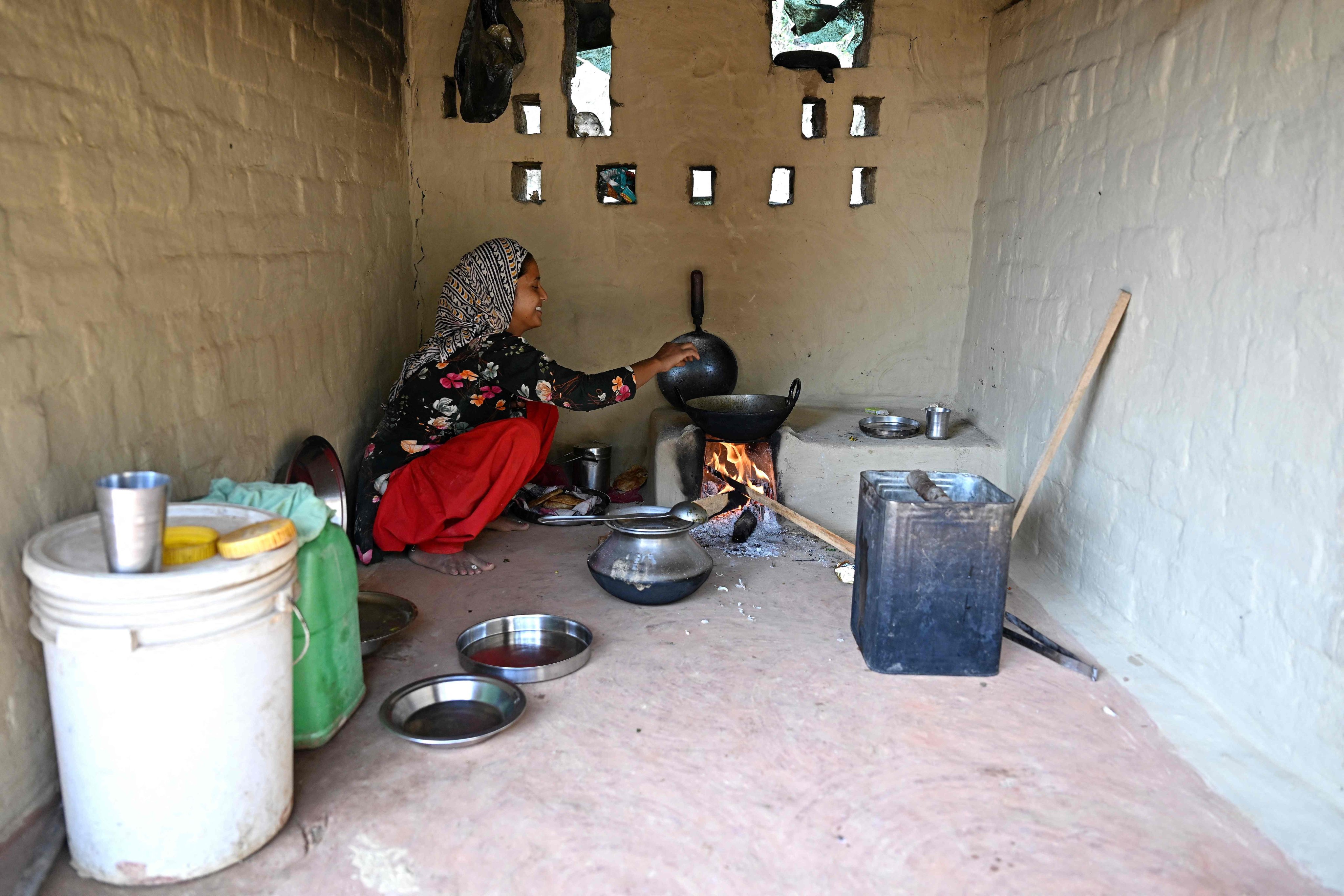 An Indian migrant worker prepares food inside a mud shelter near a brick kiln on the outskirts of Srinagar in August. Photo: AFP
