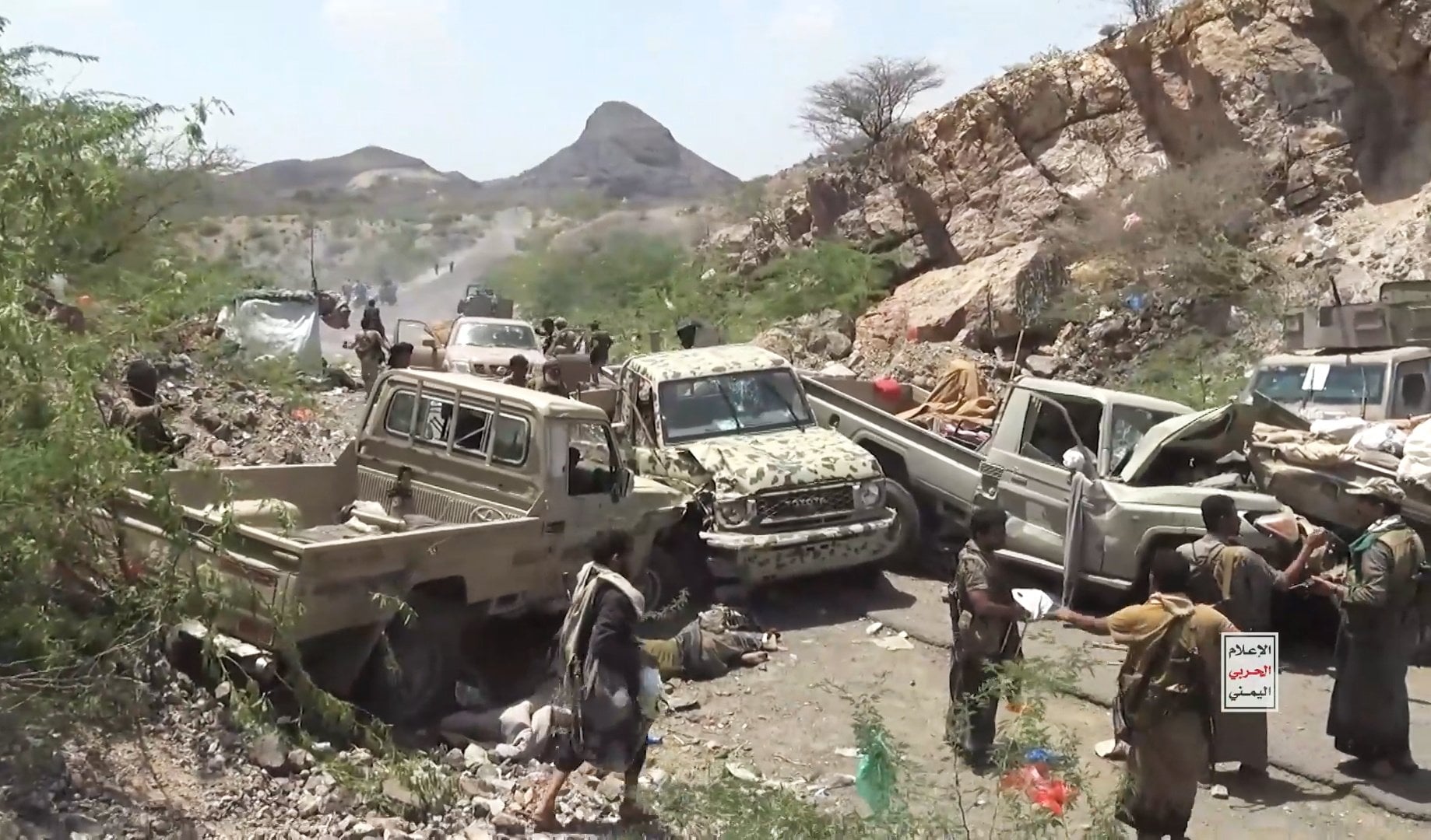Houthi fighters inspecting damaged pick-up trucks. Photo: Houthi Military Media via EPA