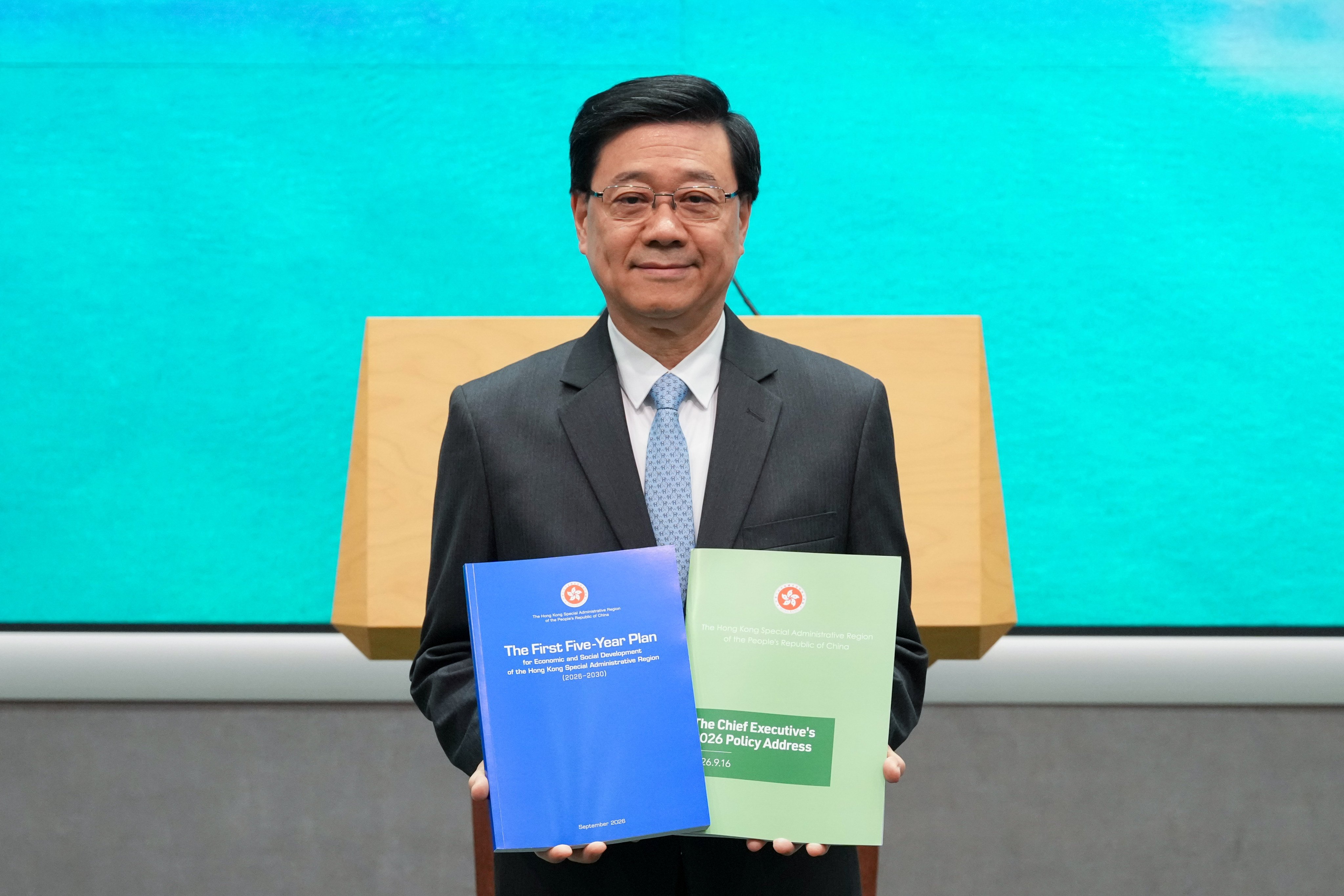 Chief Executive John Lee poses with his latest policy address and the first five-year plan. Photo: Karma Lo