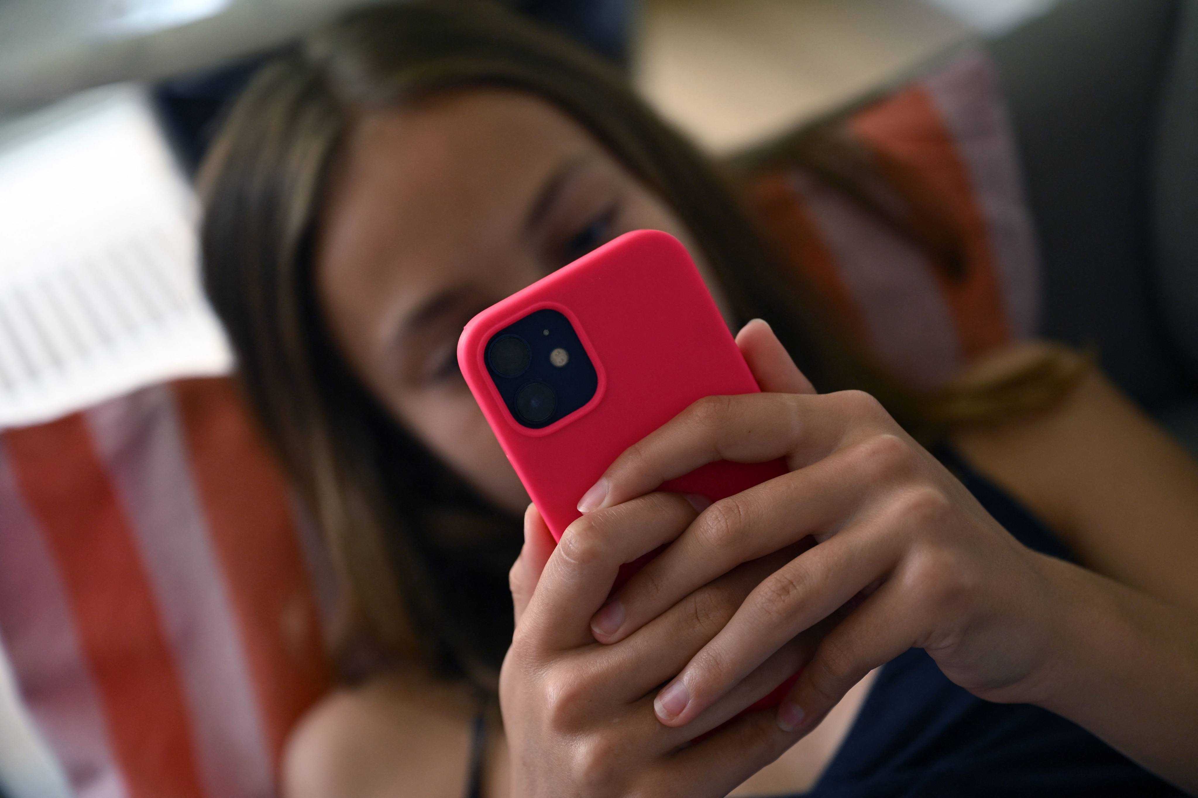 A teenager looks at her smartphone in Brussels. The EU already has powerful laws to protect children including the content rules known as the Digital Services Act. Photo: AFP