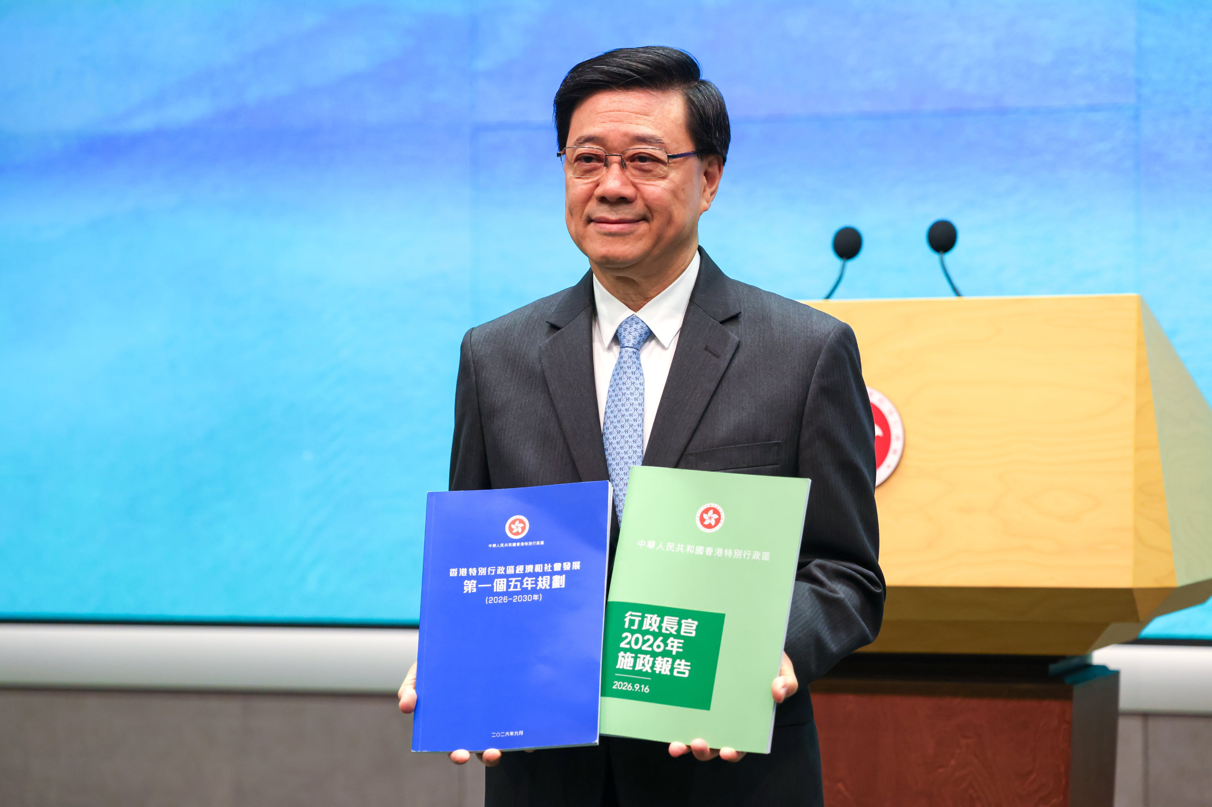 Chief Executive John Lee holds up copies of the booklets detailing Hong Kong’s first five-year plan, with a blue cover, and the policy address, which retains its iconic green design, at the government’s headquarters in Admiralty, on September 15. Photo: Silvia Siu