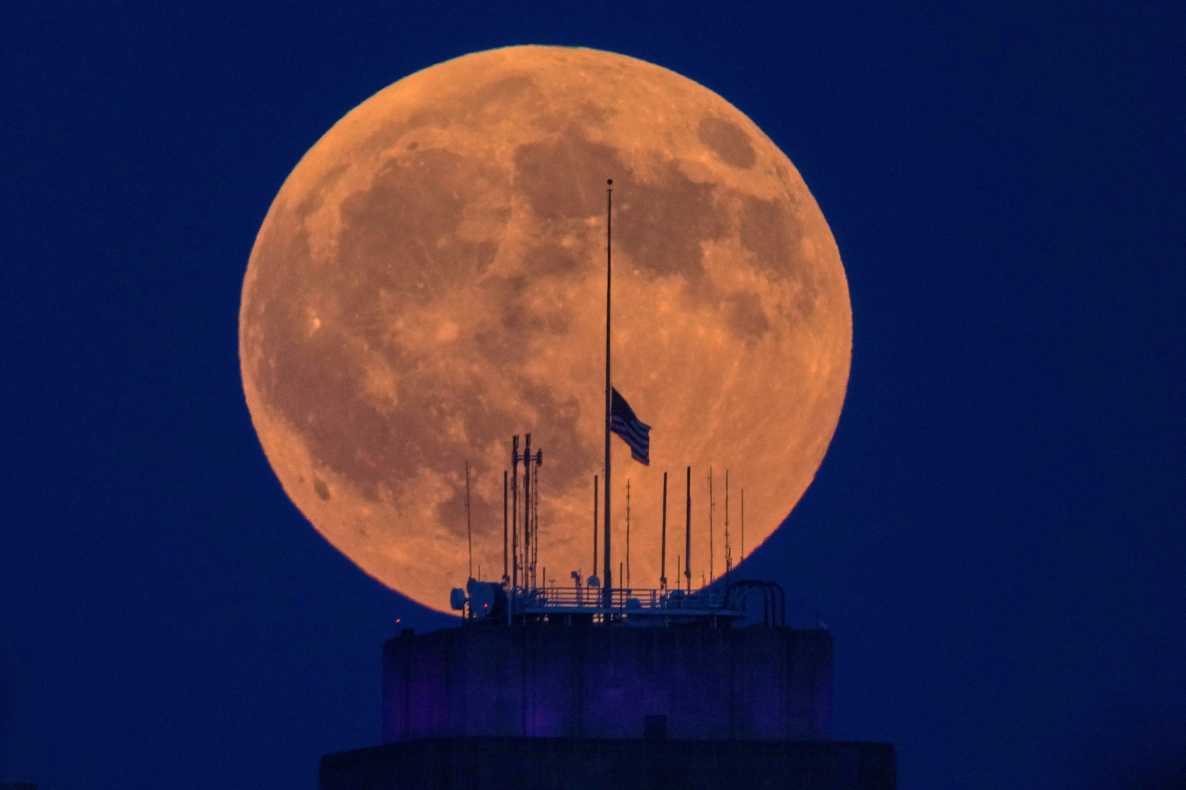 A full moon rises beyond an American flag. Photo: AP
