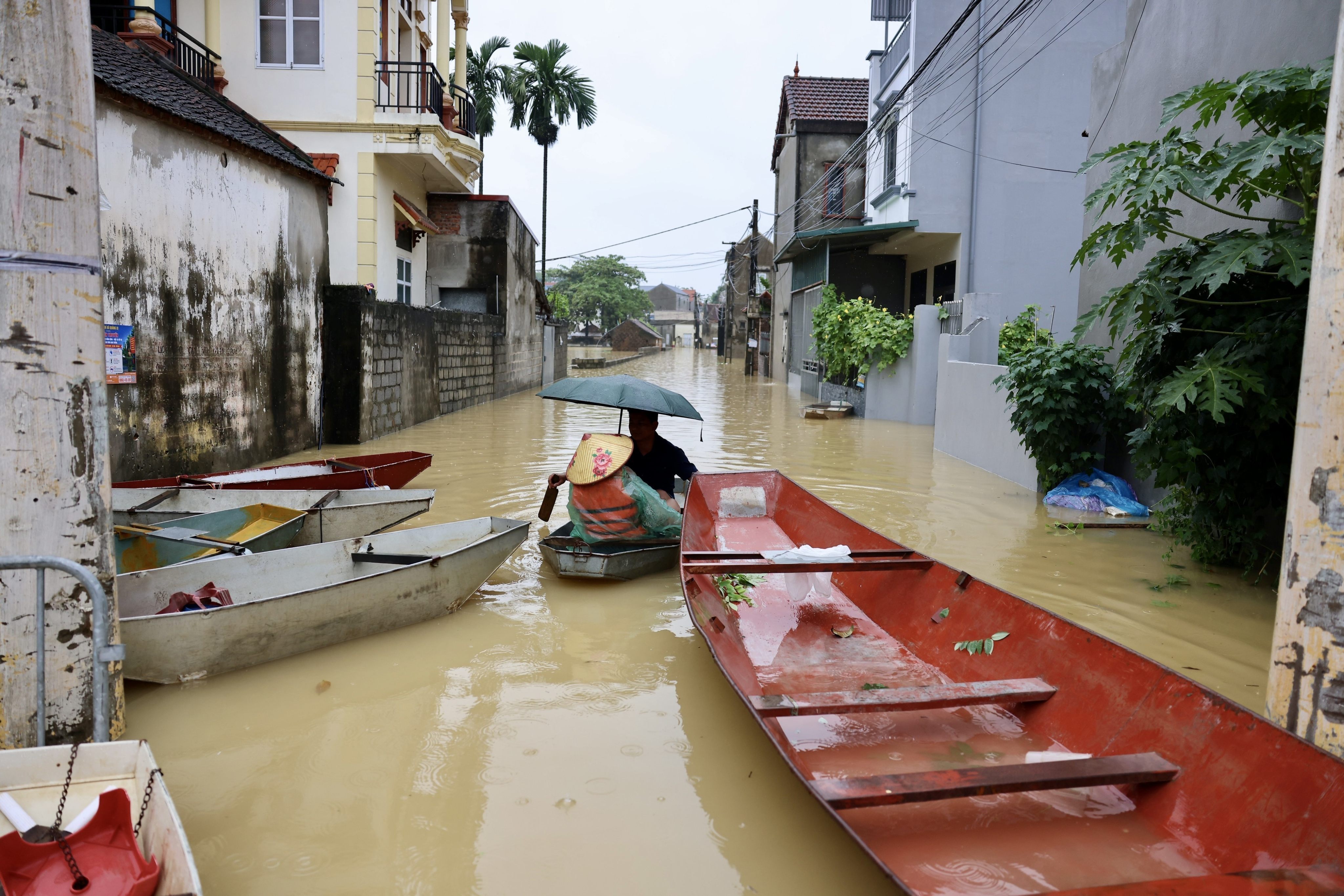 Local residents commute by boat through a flooded village on the outskirts of Hanoi on Thursday. Photo: VNA / AP